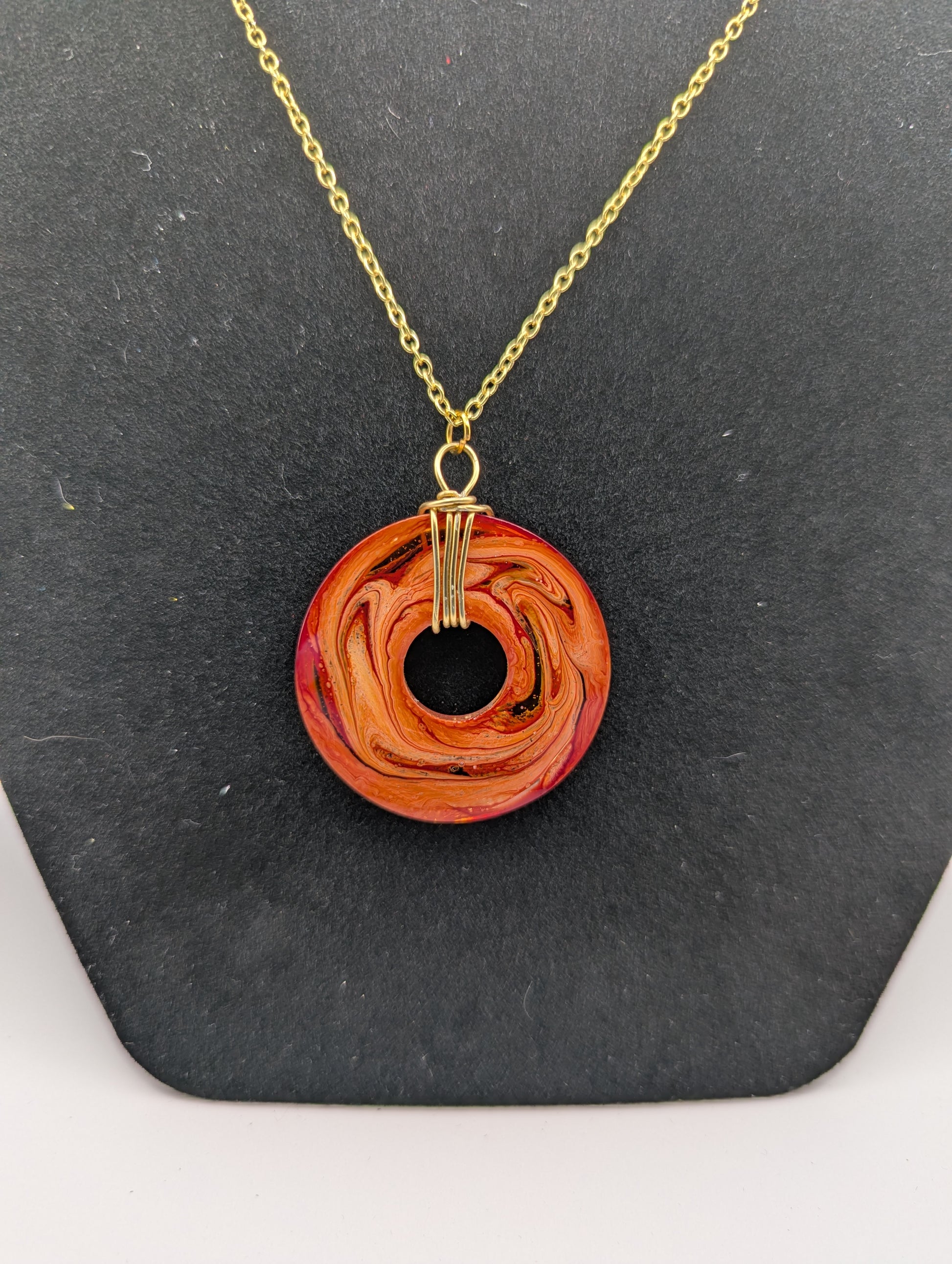 Back view of Wire Wrapped Donut Resin Pendant Necklace - Petri Effect with shades of orange & red swirls. Resin Necklace on a gold plated chain.