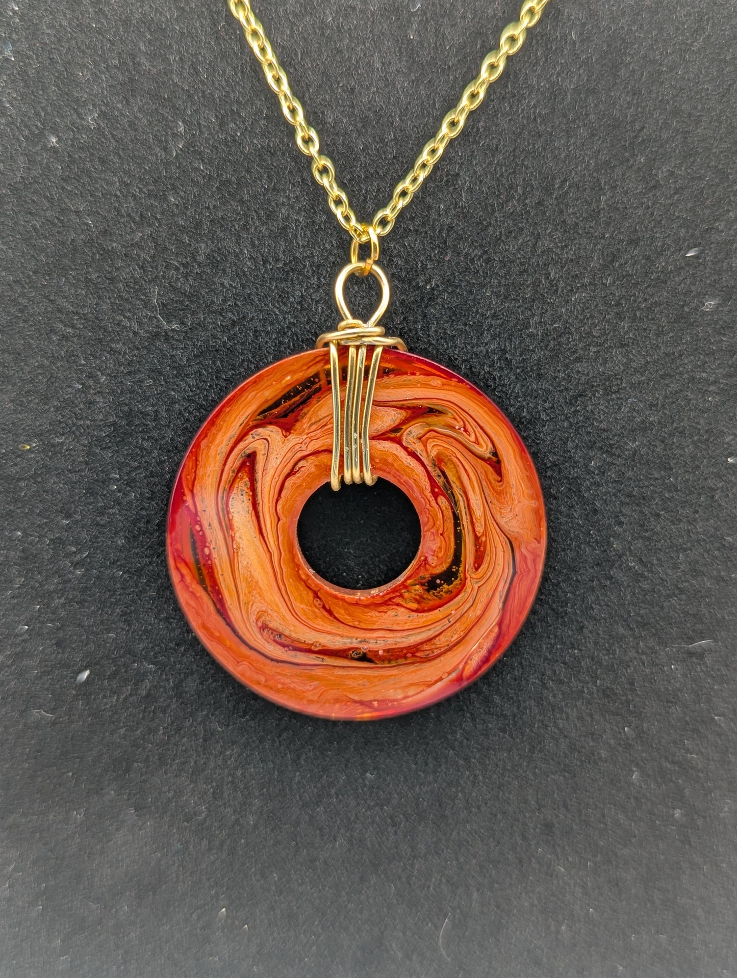 Back view of Wire Wrapped Donut Resin Pendant Necklace - Petri Effect with shades of orange & red swirls. Resin Necklace on a gold plated chain.