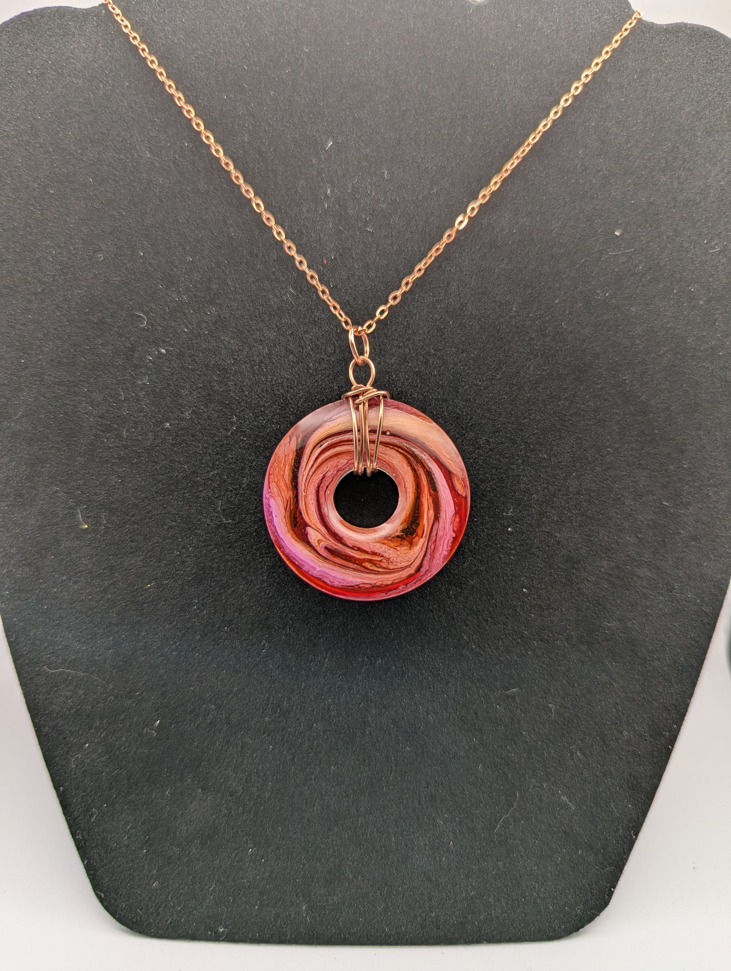 Back view of Wire Wrapped Donut Resin Pendant Necklace - Petri Effect with shades of orange, pink, & red swirls. Resin Necklace on a rose gold colored stainless steel plated metal chain.