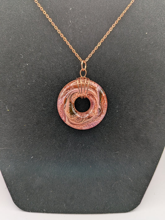 Wire Wrapped Donut Resin Pendant Necklace - Petri Effect with shades of orange, pink, & red swirls. Resin Necklace on a rose gold colored stainless steel plated metal chain.