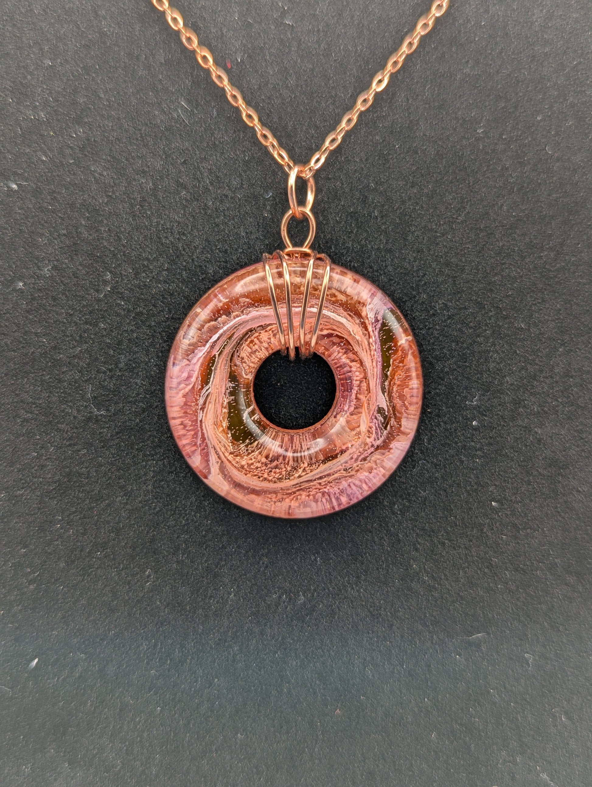 Wire Wrapped Donut Resin Pendant Necklace - Petri Effect with shades of orange, pink, & red swirls. Resin Necklace on a rose gold colored stainless steel plated metal chain.