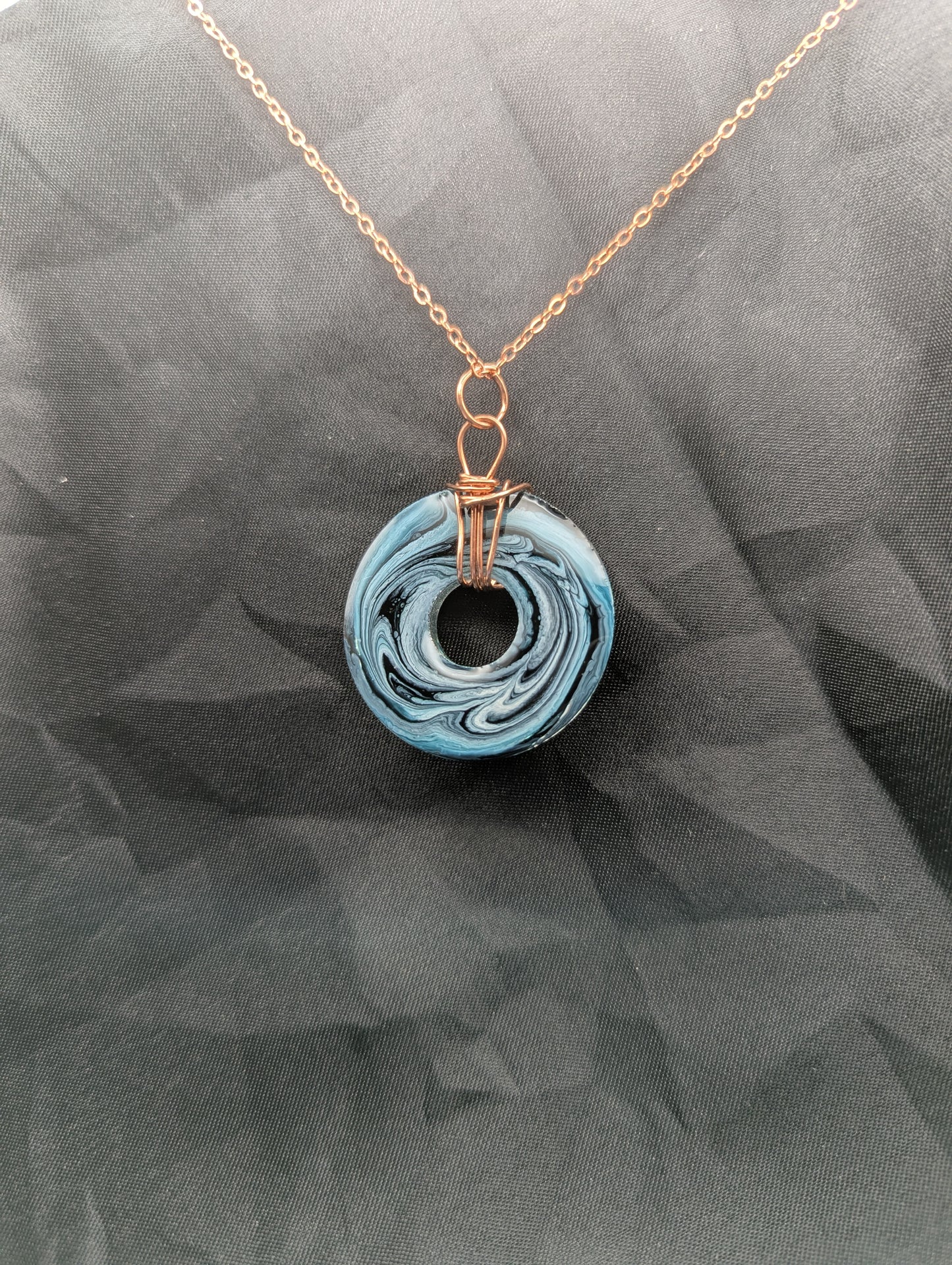 Back view of Wire Wrapped Donut Resin Pendant Necklace - Petri Effect with shades of blue & black swirls. Resin Necklace on copper plated stainless steel chain.