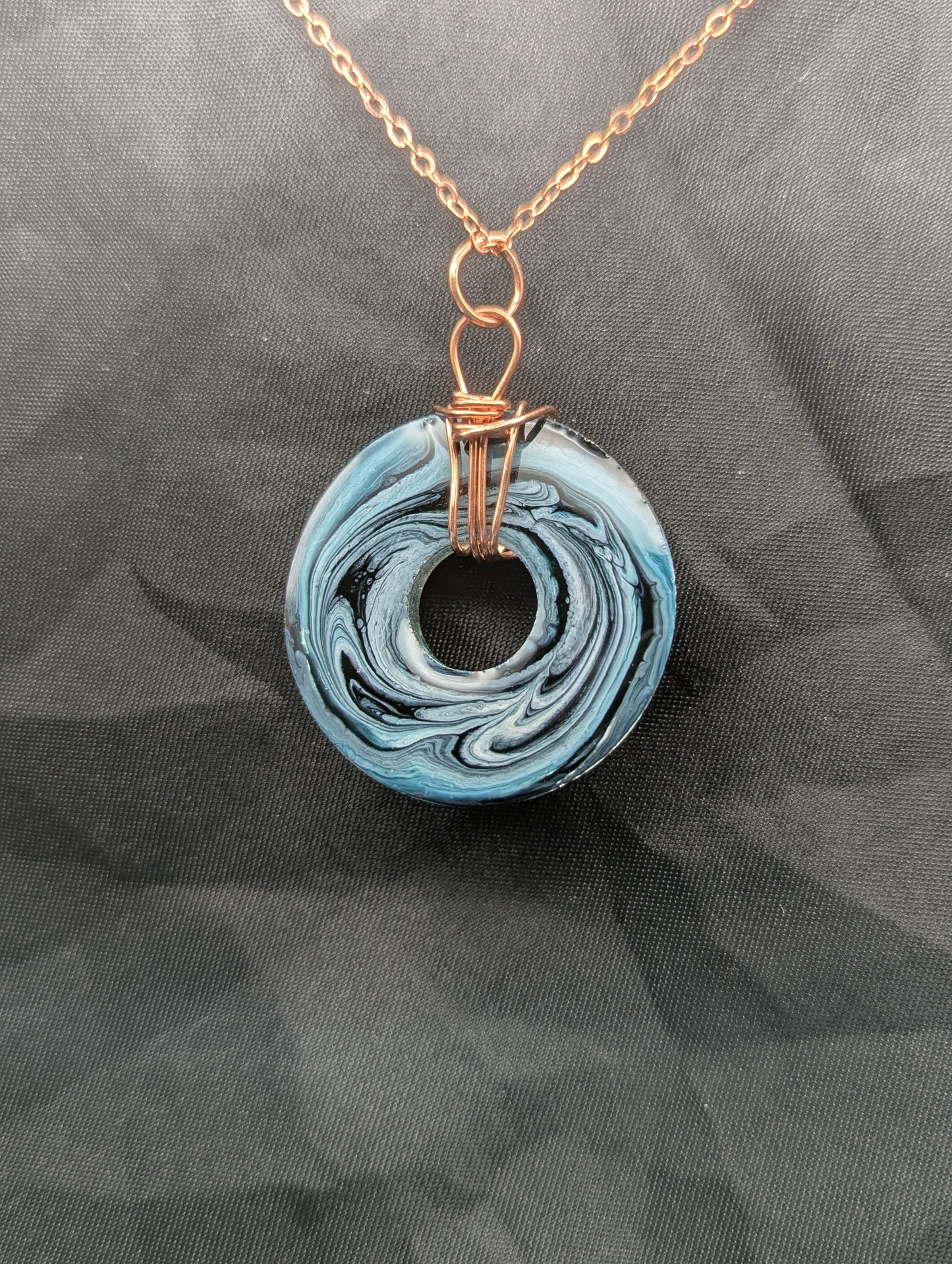 Back view of Wire Wrapped Donut Resin Pendant Necklace - Petri Effect with shades of blue & black swirls. Resin Necklace on copper plated stainless steel chain.