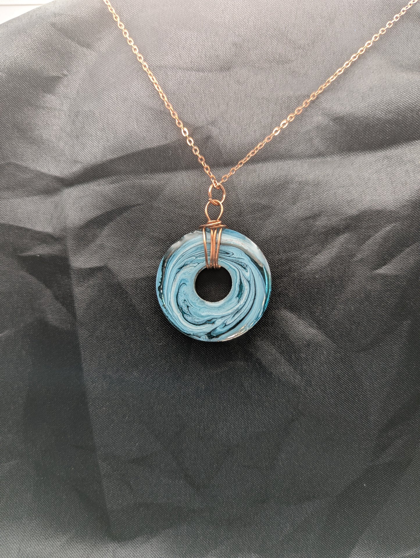 Back view of Wire Wrapped Donut Resin Pendant Necklace - Petri Effect with shades of blue & metallic bronze swirls. Resin Necklace on a rose gold colored stainless steel metal chain