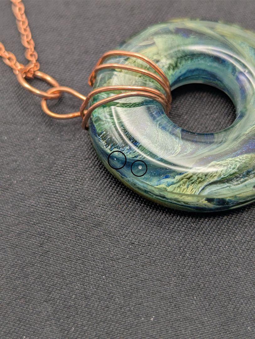 Wire Wrapped Donut Resin Pendant Necklace - Petri Effect with shades of blue, green, & yellow swirls. Resin Necklace on a rose gold colored stainless steel metal chain.