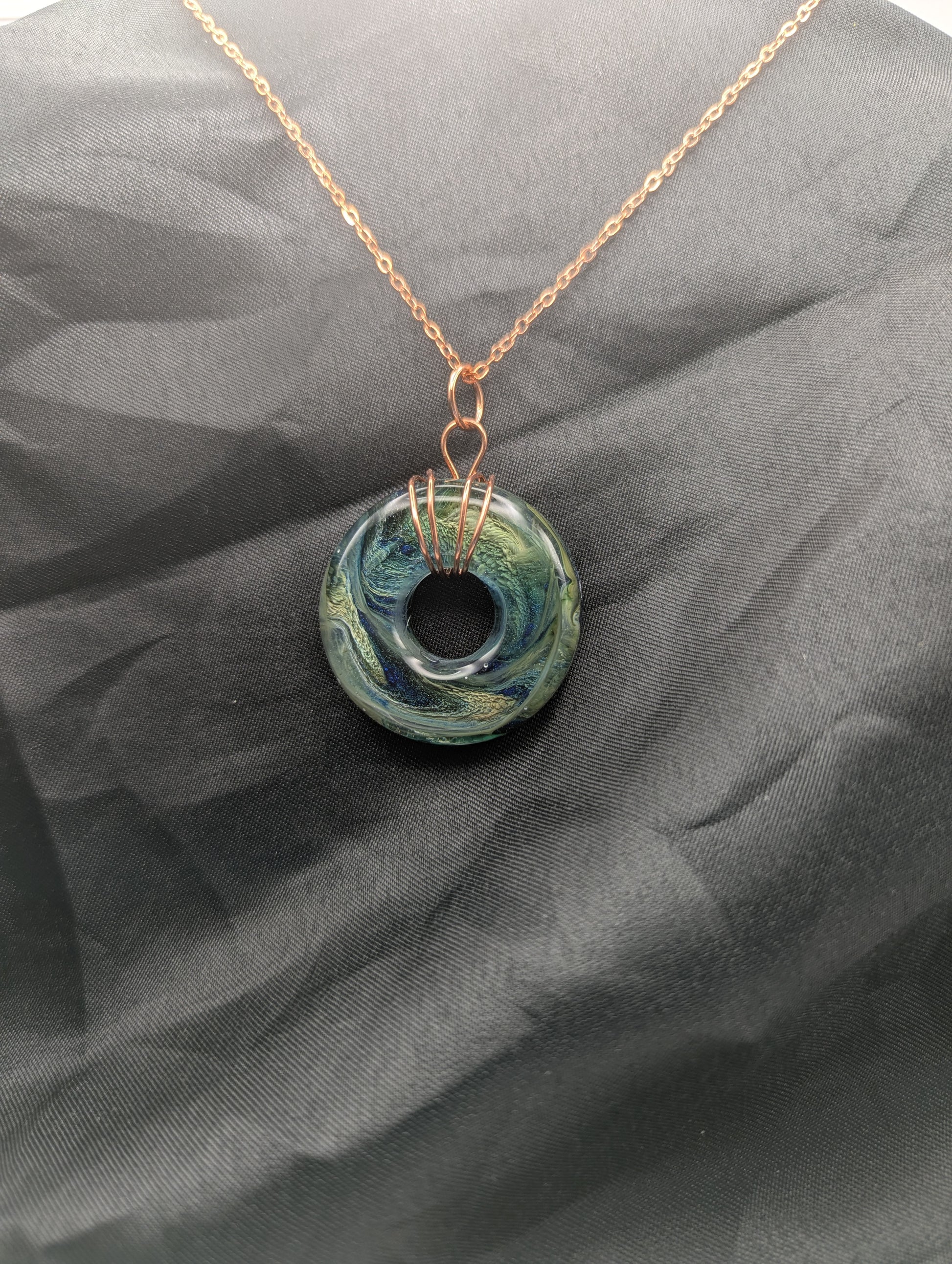 Wire Wrapped Donut Resin Pendant Necklace - Petri Effect with shades of blue, green, & yellow swirls. Resin Necklace on a rose gold colored stainless steel metal chain.
