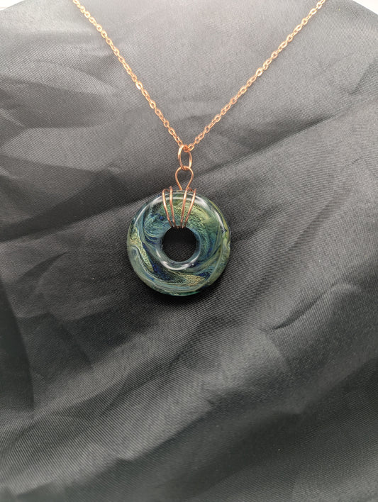 Wire Wrapped Donut Resin Pendant Necklace - Petri Effect with shades of blue, green, & yellow swirls. Resin Necklace on a rose gold colored stainless steel metal chain.