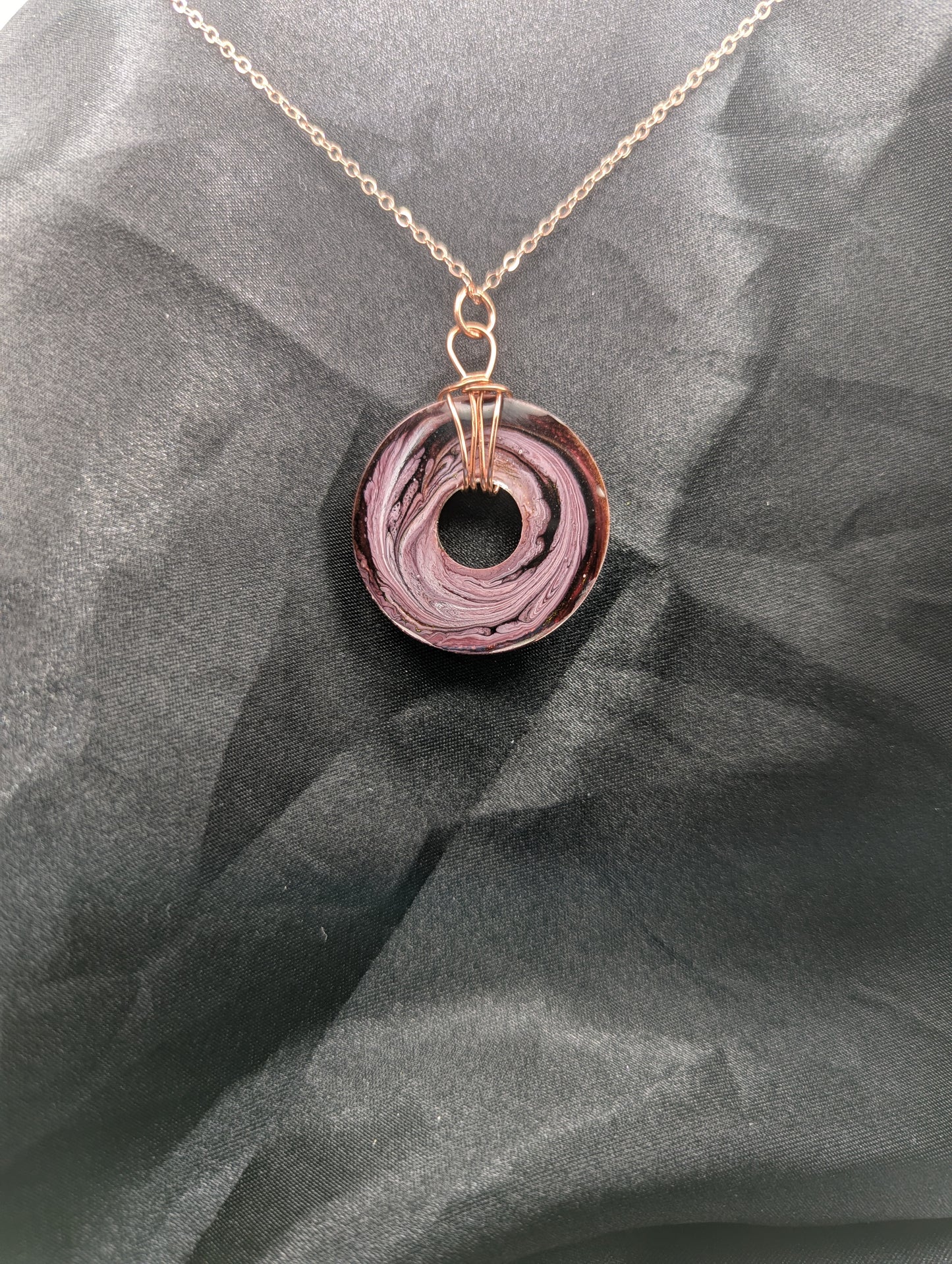 Back view of Wire Wrapped Donut Resin Pendant Necklace - Petri Effect with shades of pink & purple swirls. Resin Necklace on a rose gold colored stainless steel plated metal chain.