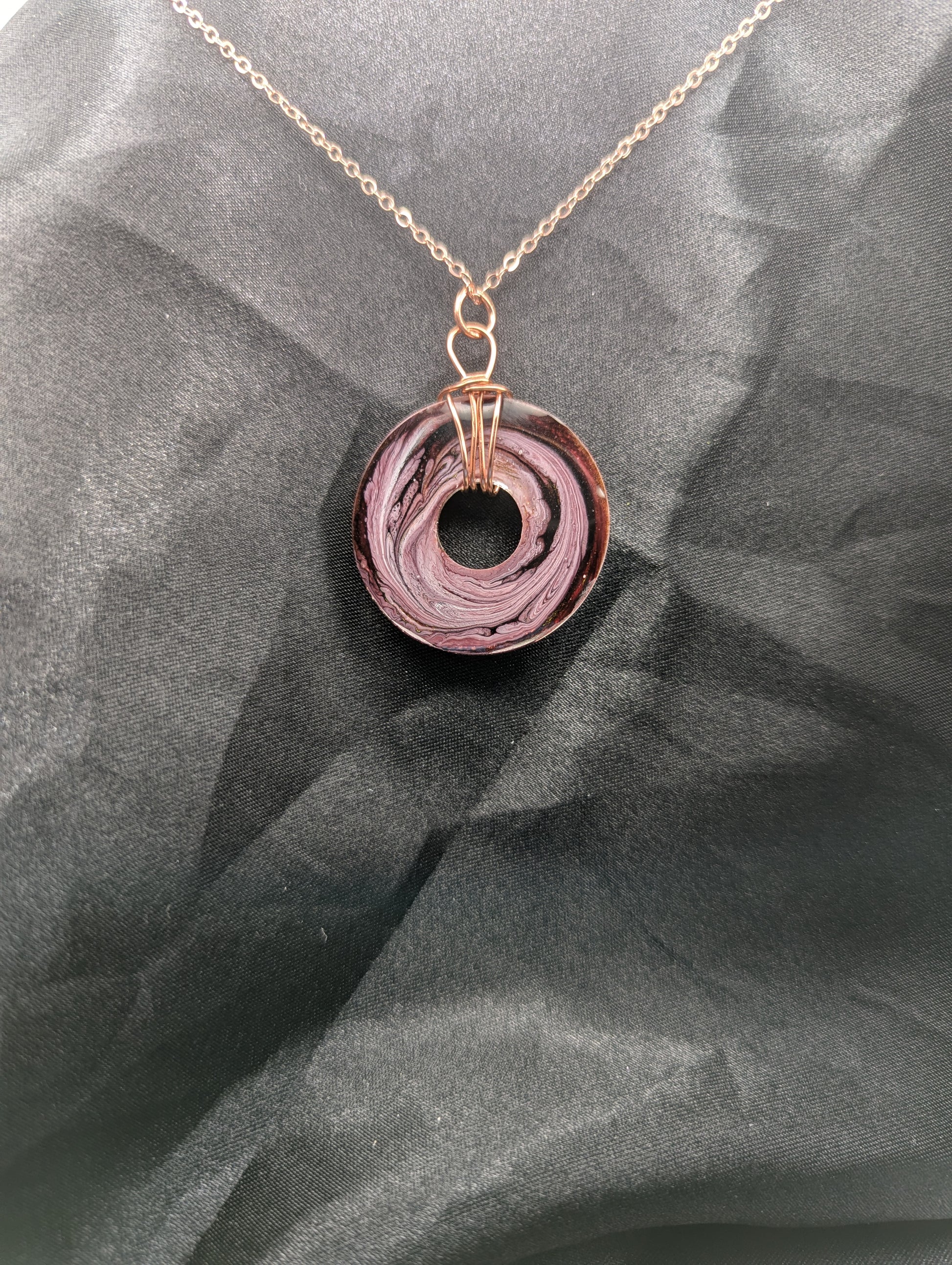 Back view of Wire Wrapped Donut Resin Pendant Necklace - Petri Effect with shades of pink & purple swirls. Resin Necklace on a rose gold colored stainless steel plated metal chain.