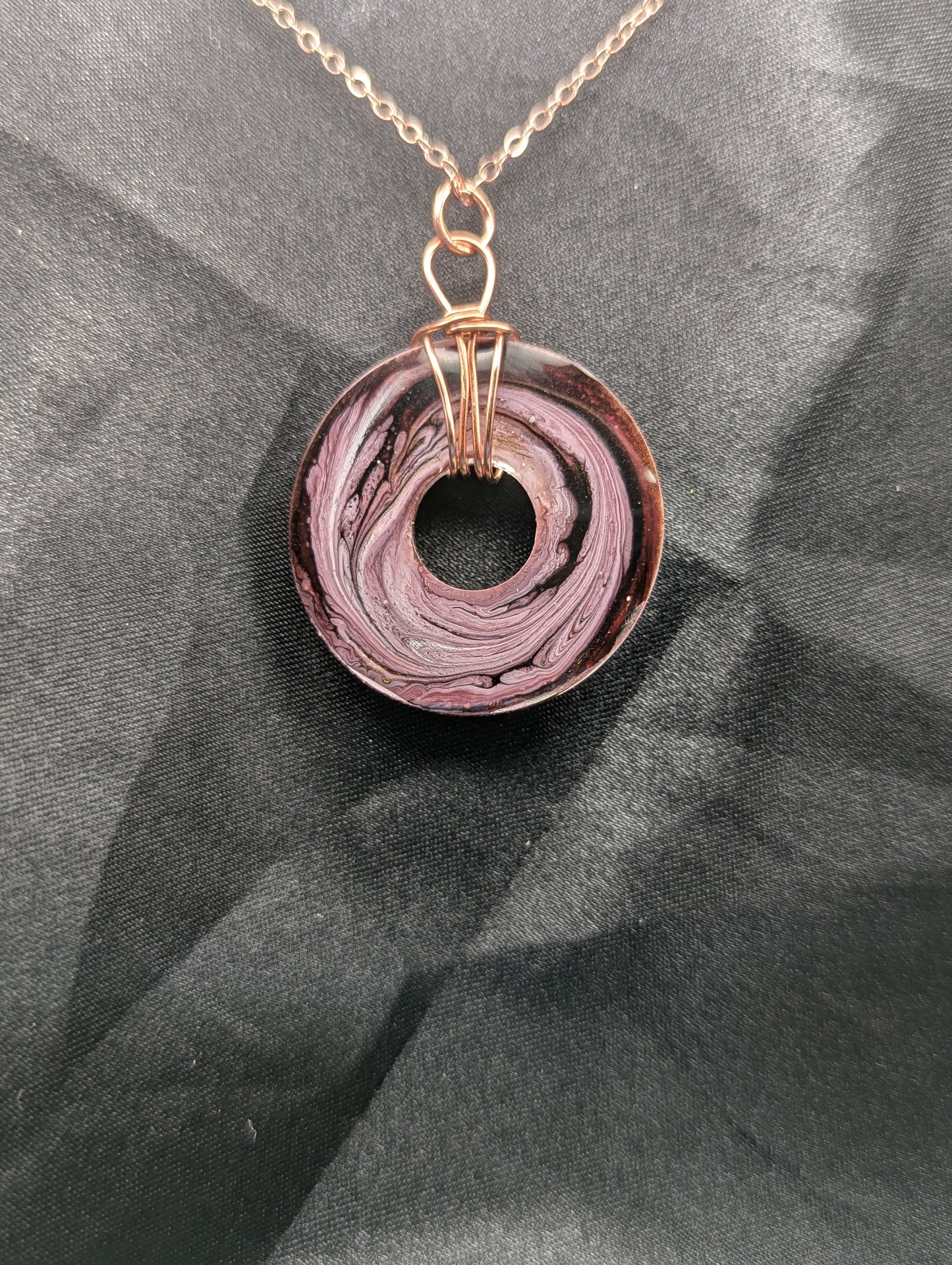 Back view of Wire Wrapped Donut Resin Pendant Necklace - Petri Effect with shades of pink & purple swirls. Resin Necklace on a rose gold colored stainless steel plated metal chain.