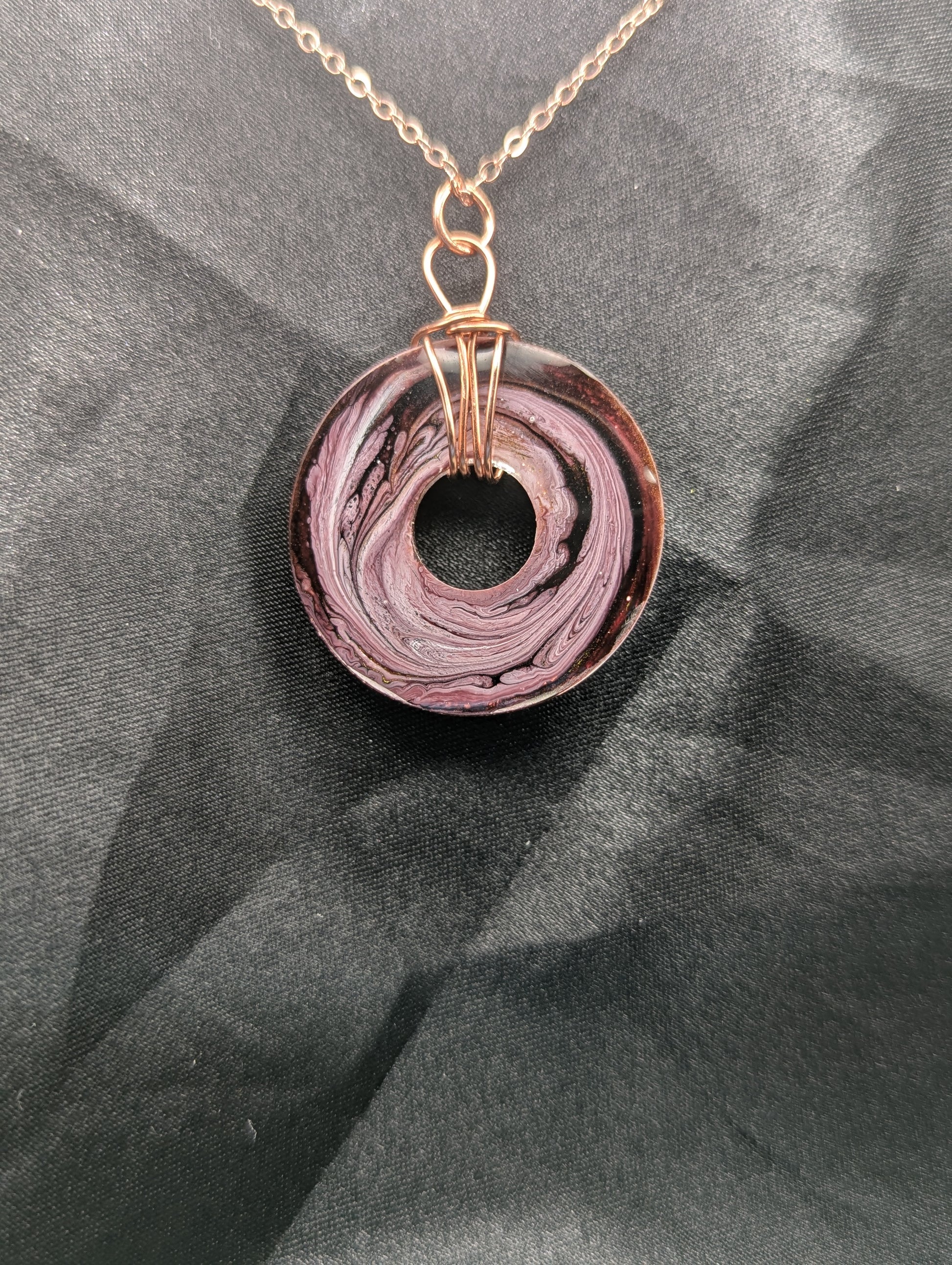 Back view of Wire Wrapped Donut Resin Pendant Necklace - Petri Effect with shades of pink & purple swirls. Resin Necklace on a rose gold colored stainless steel plated metal chain.