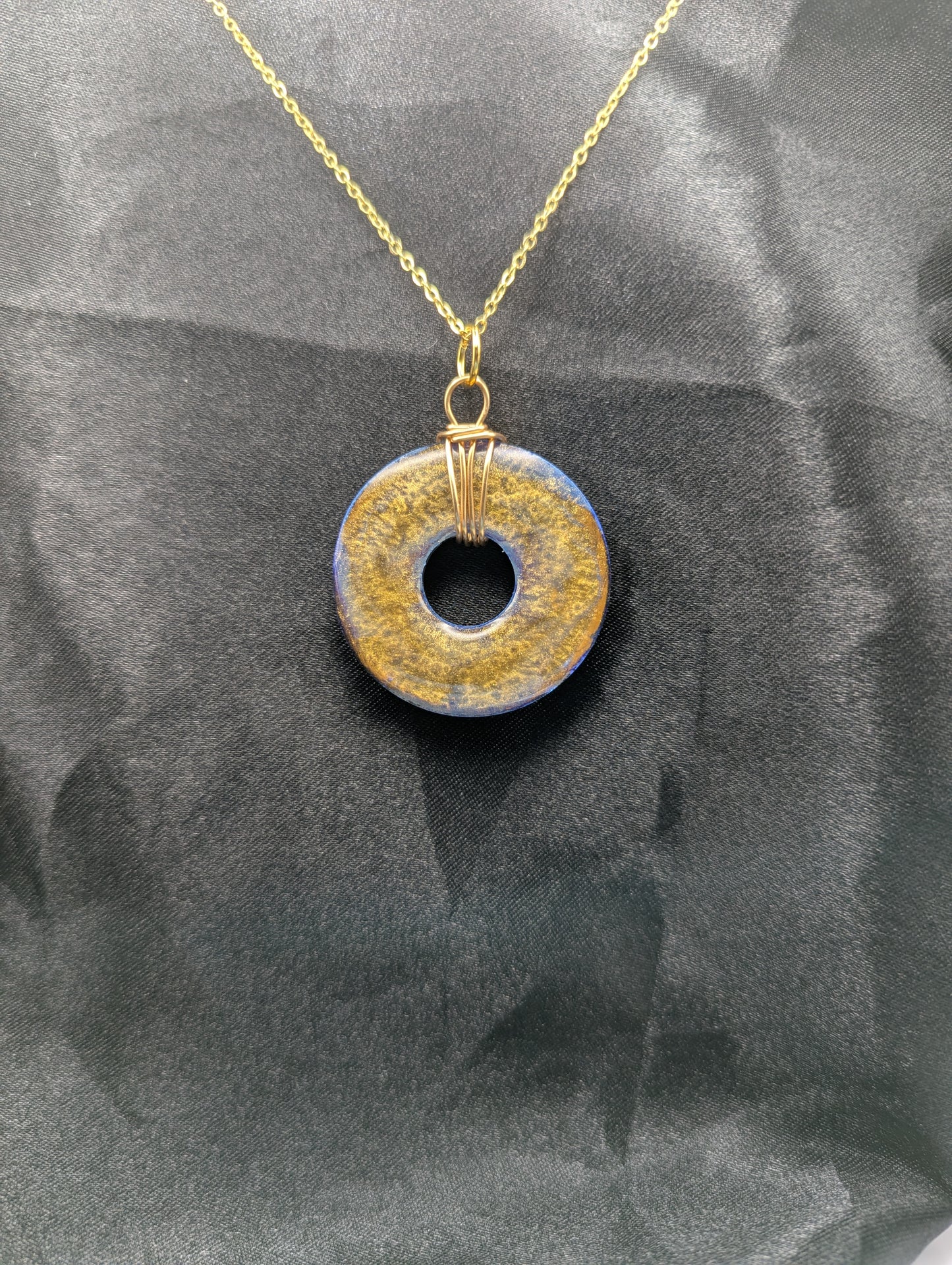 Back view of Wire Wrapped Donut Resin Pendant Necklace - Petri Effect with shades of blue & bronze swirls. Resin Necklace on a gold plated metal chain.