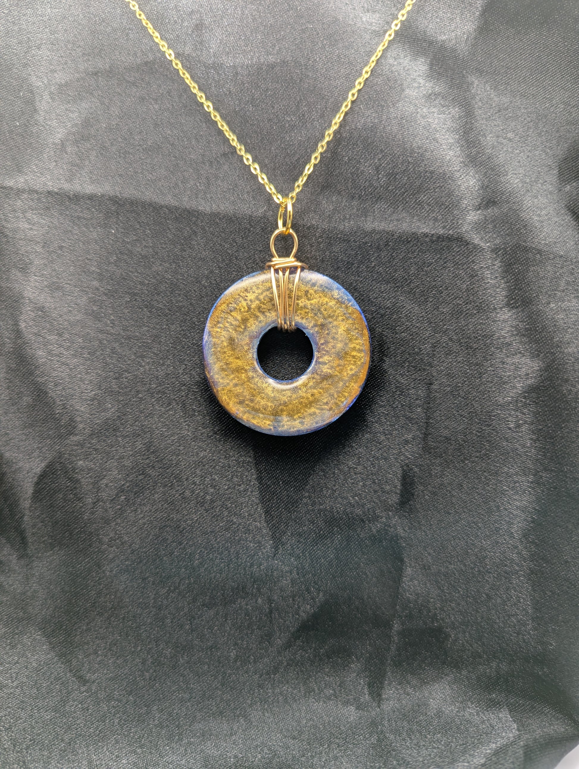 Back view of Wire Wrapped Donut Resin Pendant Necklace - Petri Effect with shades of blue & bronze swirls. Resin Necklace on a gold plated metal chain.