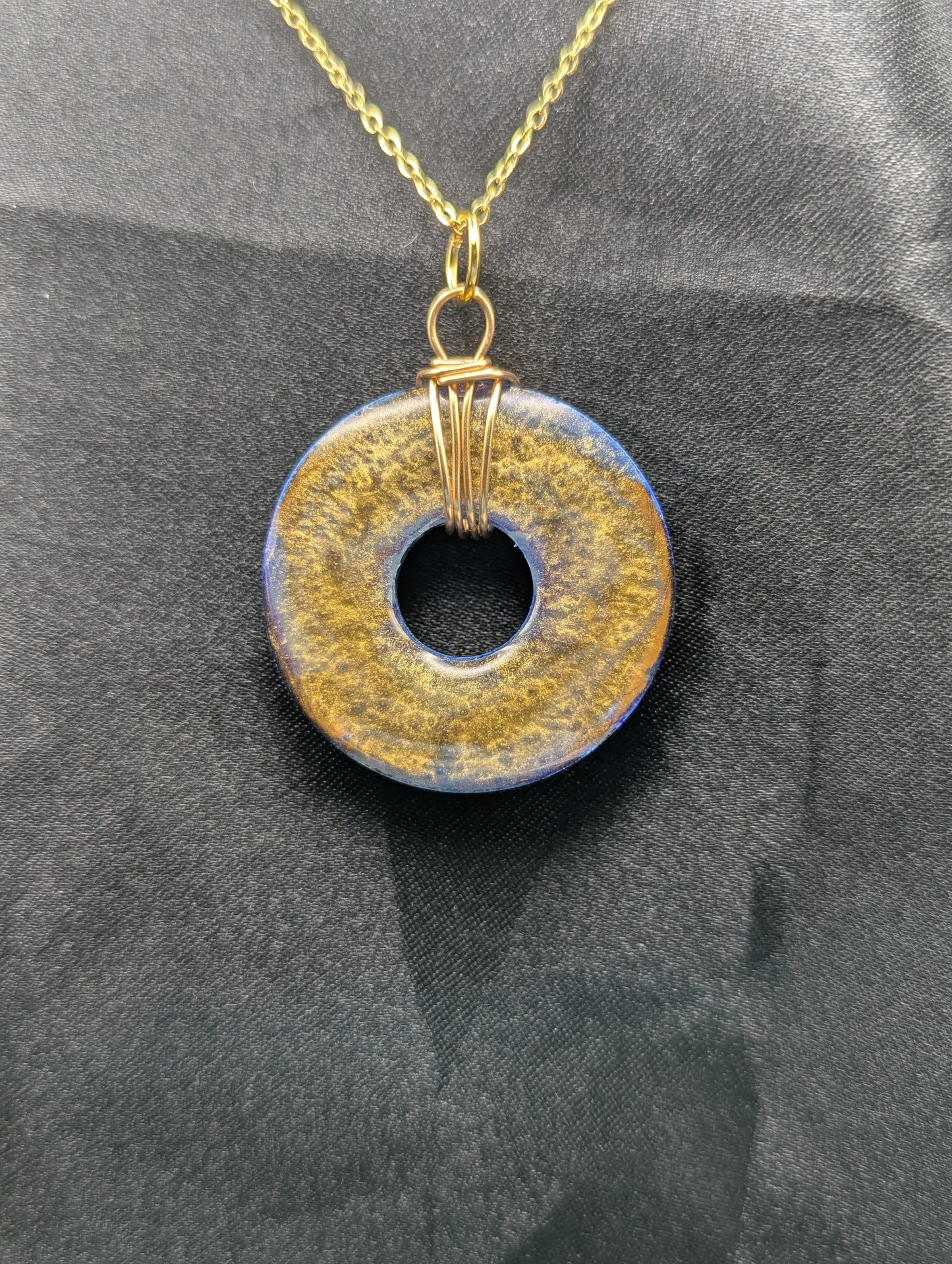 Back view of Wire Wrapped Donut Resin Pendant Necklace - Petri Effect with shades of blue & bronze swirls. Resin Necklace on a gold plated metal chain.