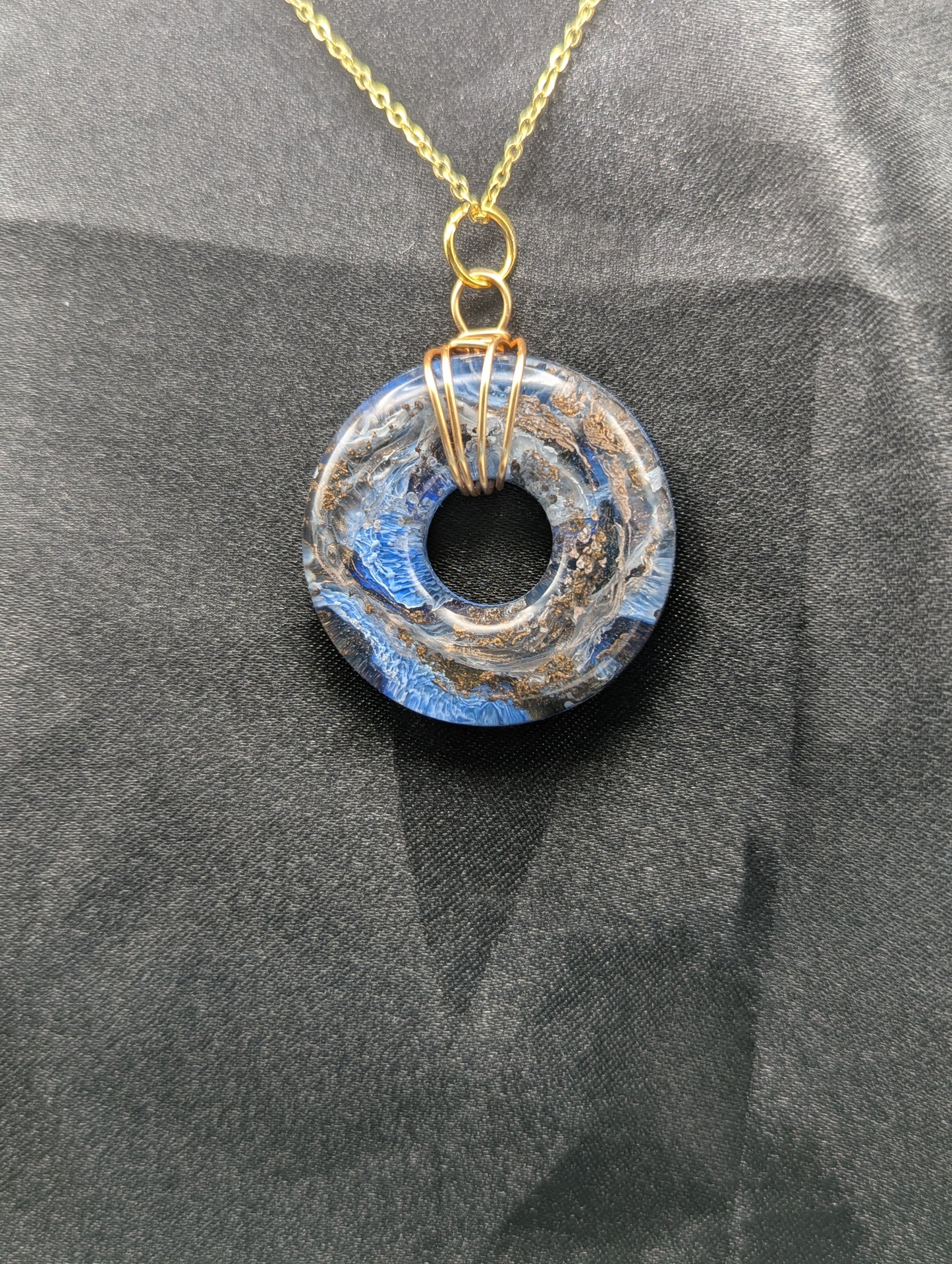 Wire Wrapped Donut Resin Pendant Necklace - Petri Effect with shades of blue & bronze swirls. Resin Necklace on a gold plated metal chain.