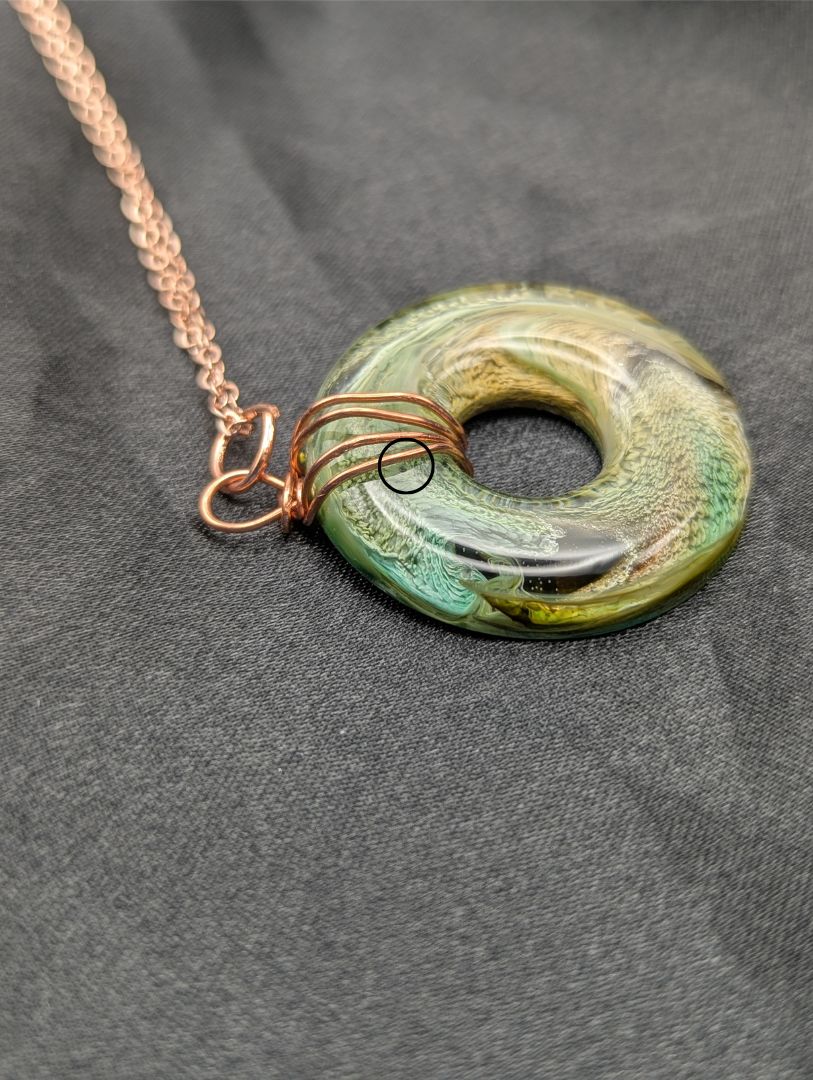 Wire Wrapped Donut Resin Pendant Necklace - Petri Effect with shades of green, yellow, & brown swirls. Resin Necklace on a rose gold colored stainless steel plated metal chain.