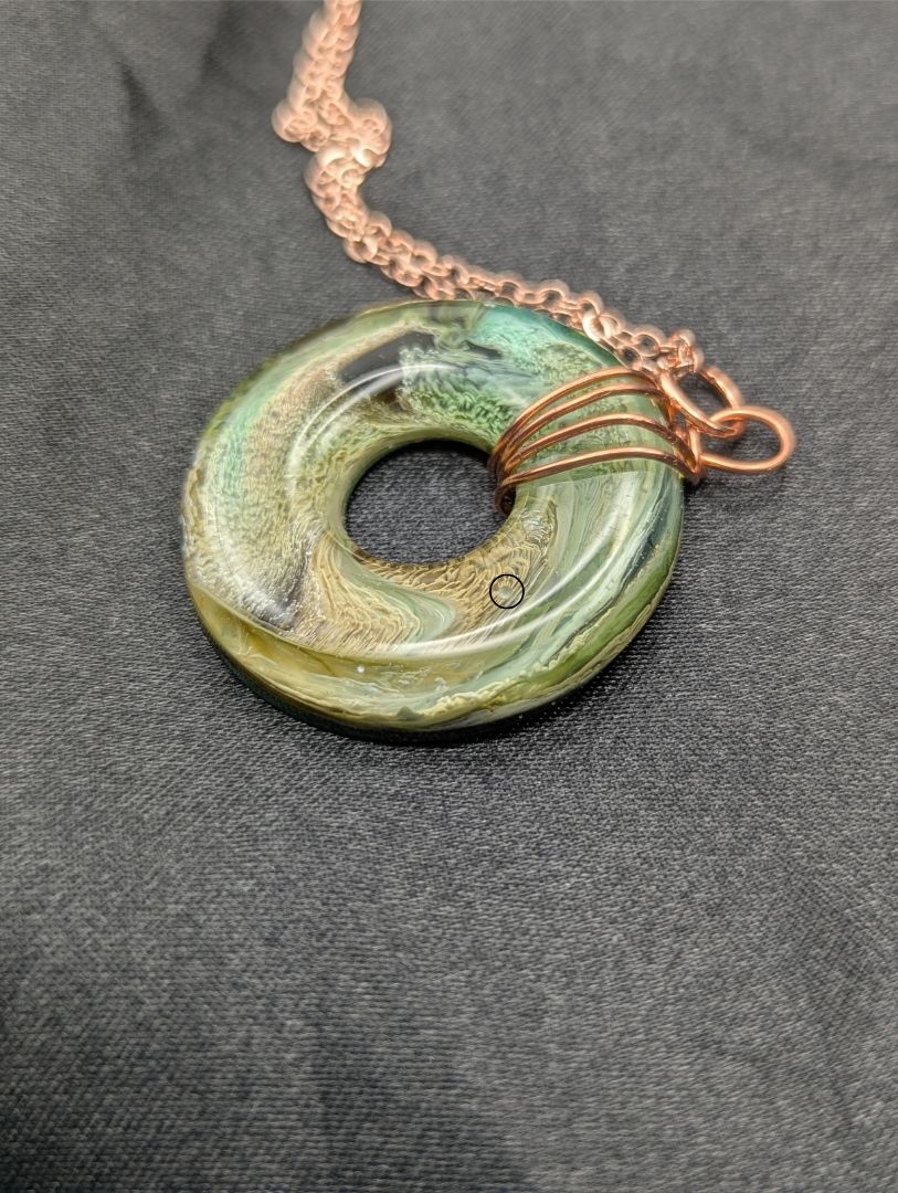 Wire Wrapped Donut Resin Pendant Necklace - Petri Effect with shades of green, yellow, & brown swirls. Resin Necklace on a rose gold colored stainless steel plated metal chain.