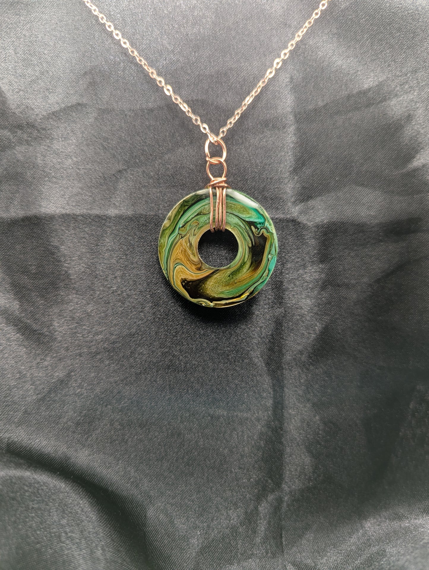 Back view of Wire Wrapped Donut Resin Pendant Necklace - Petri Effect with shades of green, yellow, & brown swirls. Resin Necklace on a rose gold colored stainless steel plated metal chain.