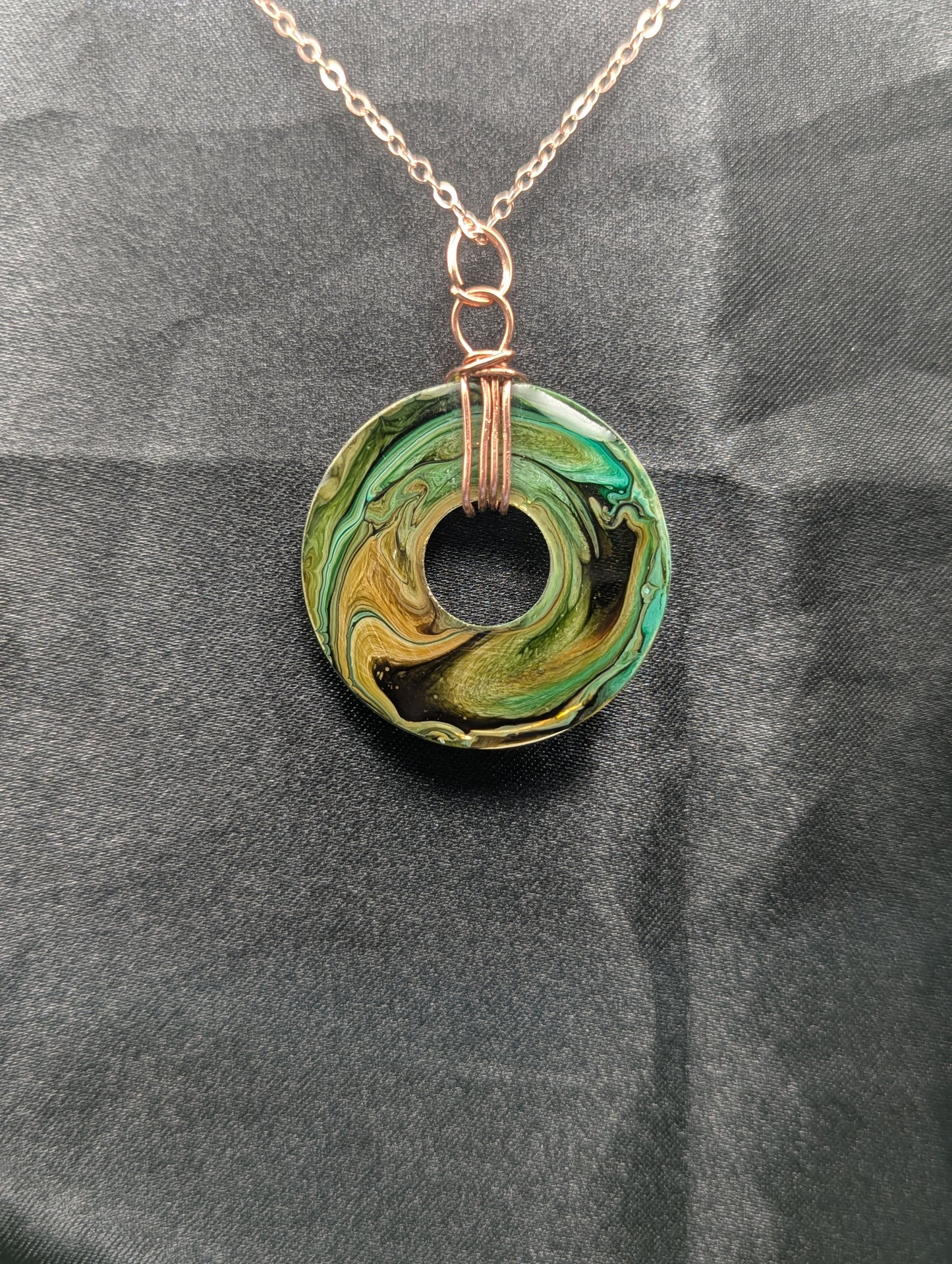 Back view of Wire Wrapped Donut Resin Pendant Necklace - Petri Effect with shades of green, yellow, & brown swirls. Resin Necklace on a rose gold colored stainless steel plated metal chain.