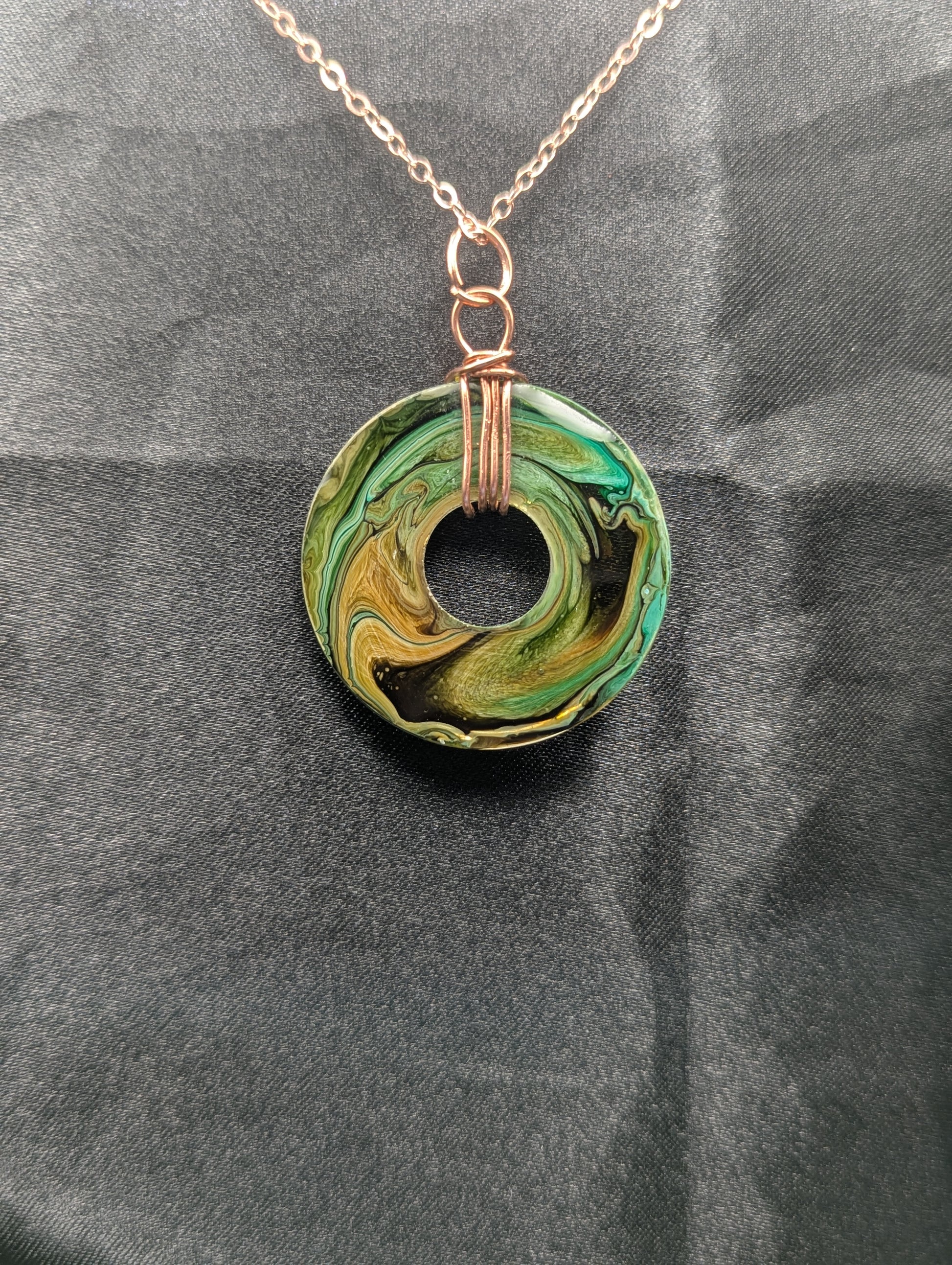 Back view of Wire Wrapped Donut Resin Pendant Necklace - Petri Effect with shades of green, yellow, & brown swirls. Resin Necklace on a rose gold colored stainless steel plated metal chain.
