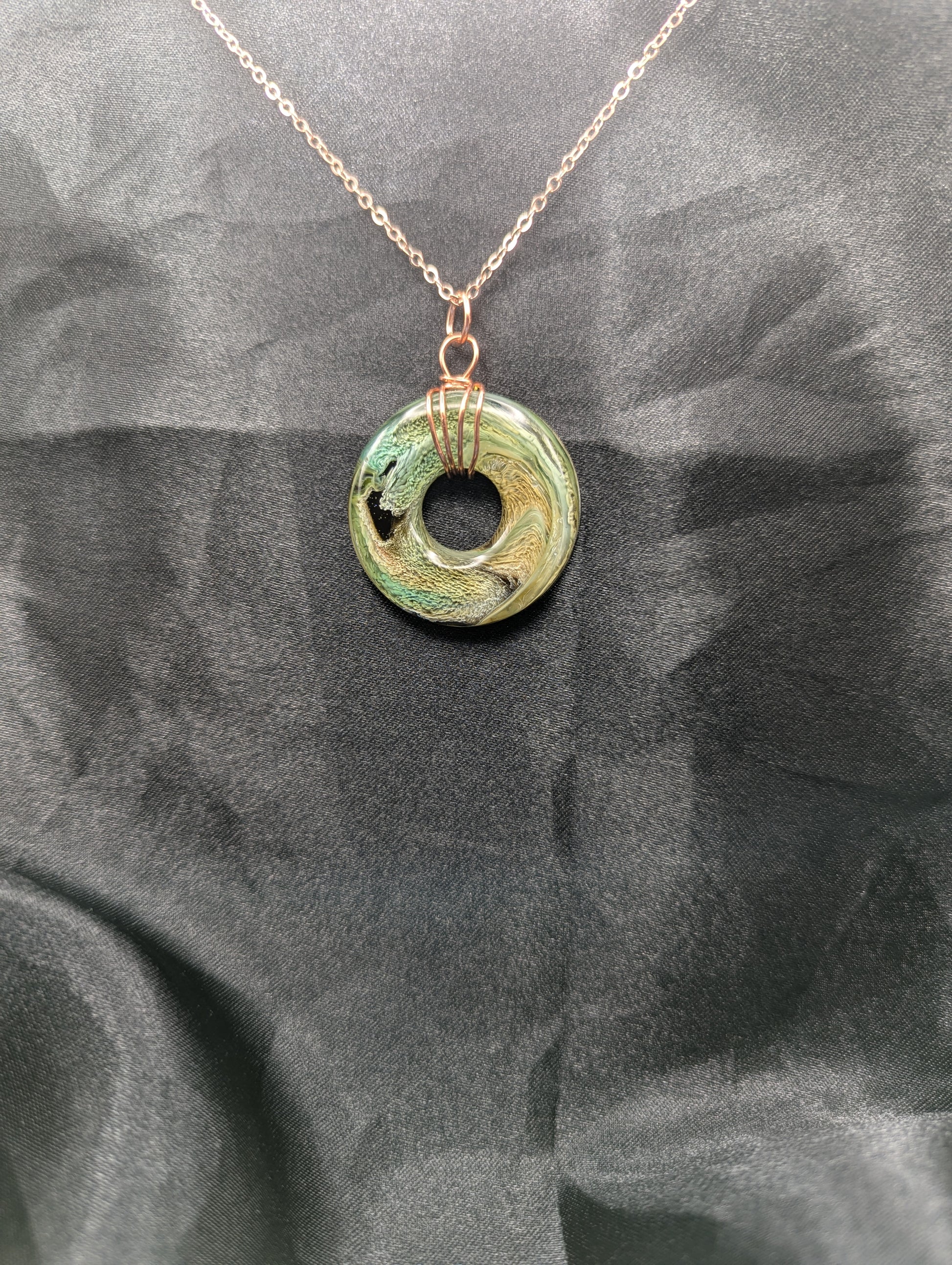 Wire Wrapped Donut Resin Pendant Necklace - Petri Effect with shades of green, yellow, & brown swirls. Resin Necklace on a rose gold colored stainless steel plated metal chain.