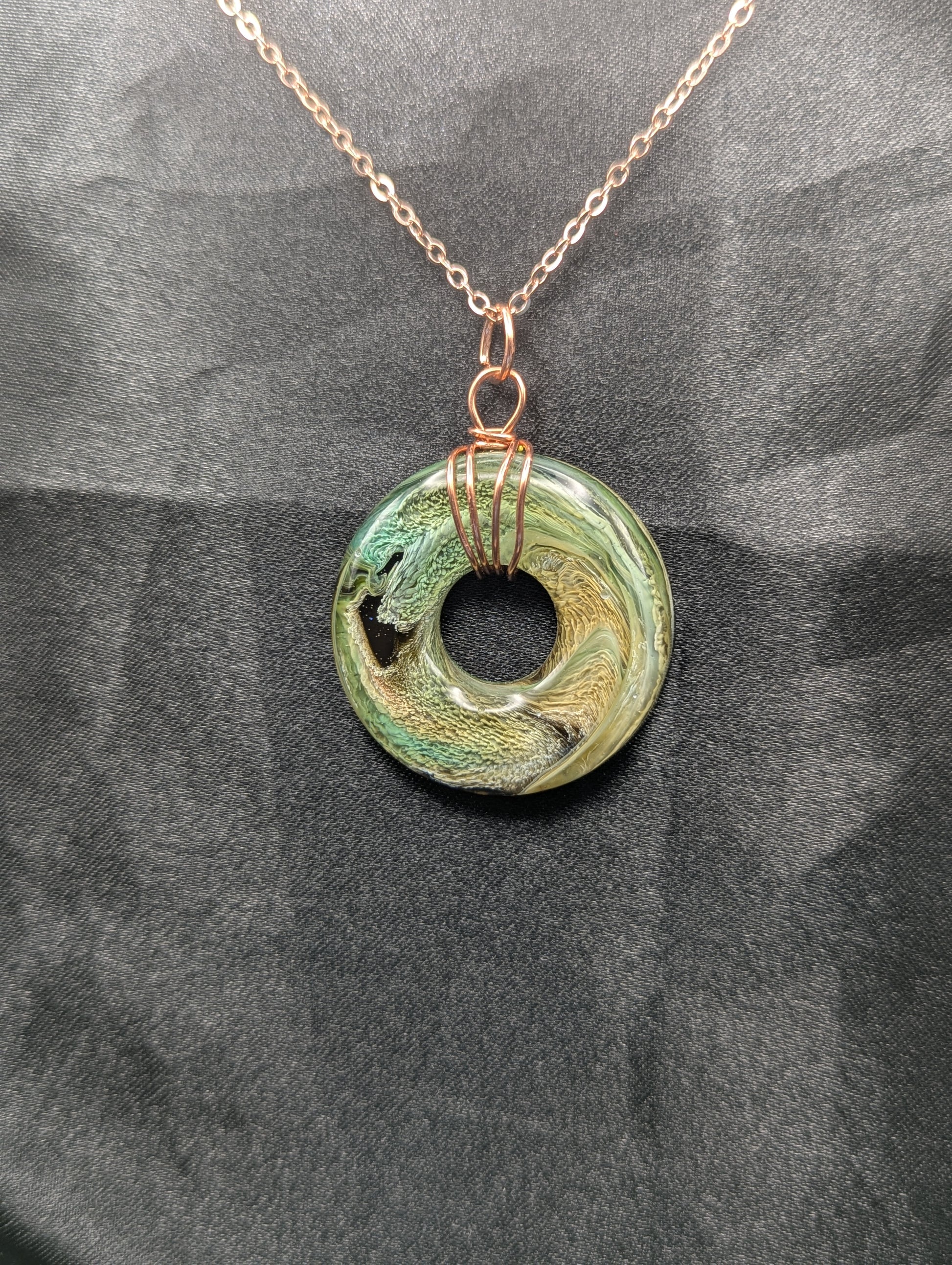 Wire Wrapped Donut Resin Pendant Necklace - Petri Effect with shades of green, yellow, & brown swirls. Resin Necklace on a rose gold colored stainless steel plated metal chain.