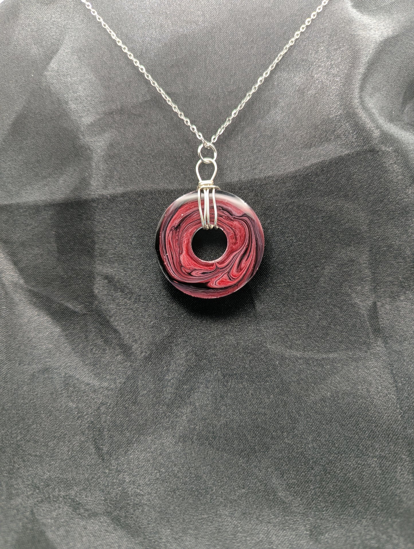 Back view of Wire Wrapped Donut Resin Pendant Necklace - Petri Effect with shades of red, pink, & black swirls. Resin Necklace on a stainless steel chain.
