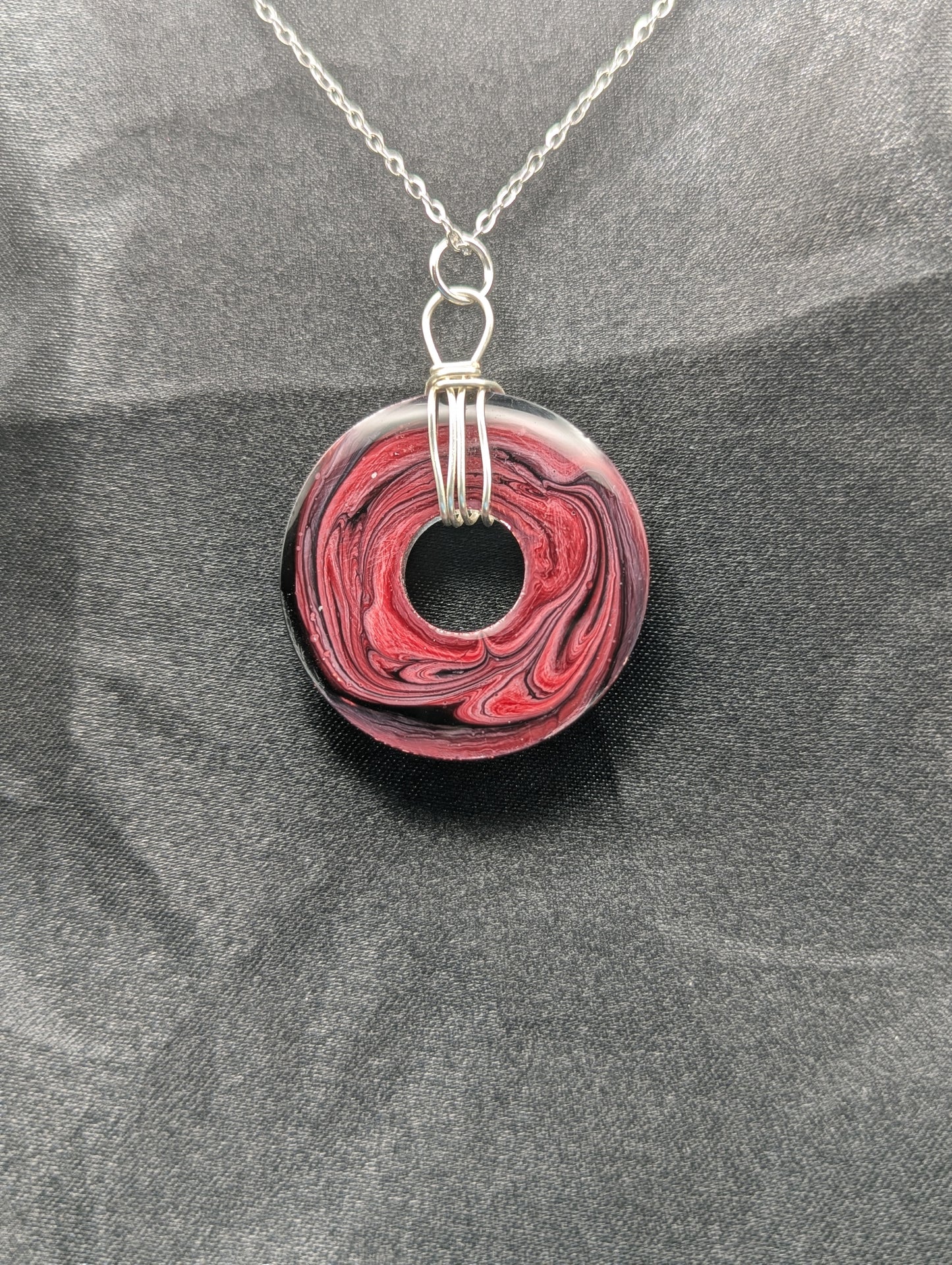 Back view of Wire Wrapped Donut Resin Pendant Necklace - Petri Effect with shades of red, pink, & black swirls. Resin Necklace on a stainless steel chain.