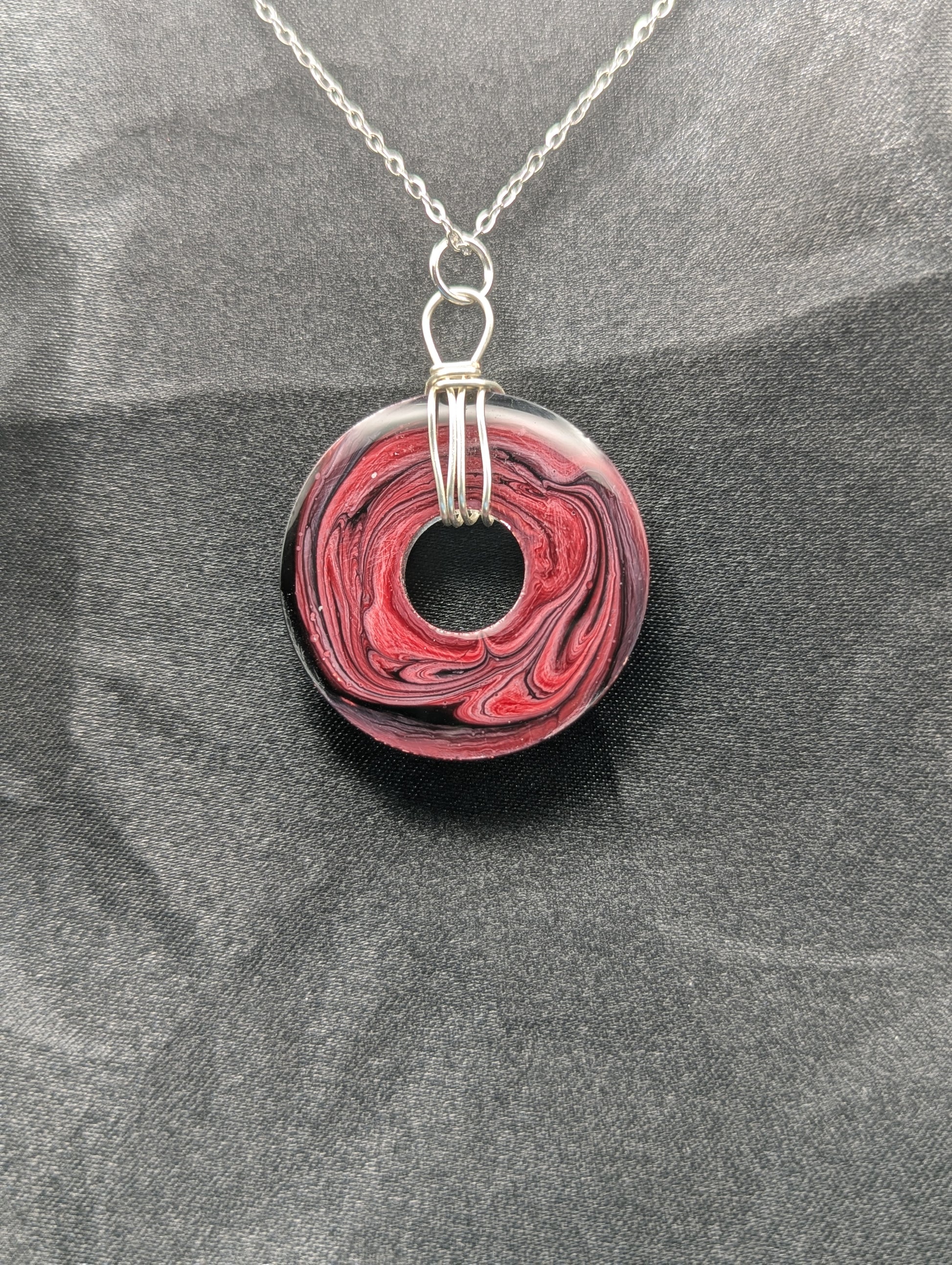 Back view of Wire Wrapped Donut Resin Pendant Necklace - Petri Effect with shades of red, pink, & black swirls. Resin Necklace on a stainless steel chain.