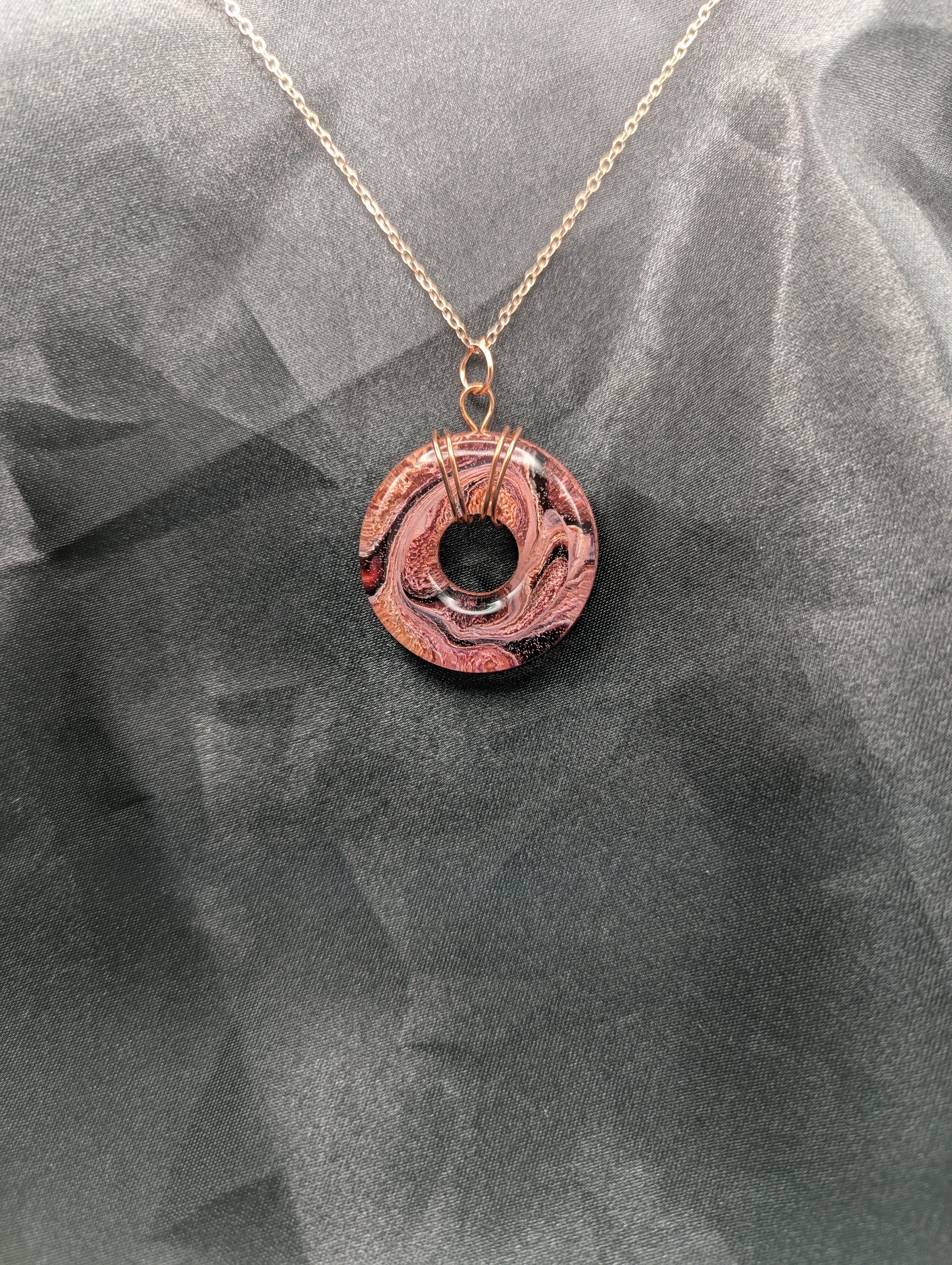Wire Wrapped Donut Resin Pendant Necklace - Petri Effect with shades of red, pink, & orange swirls. Resin Necklace on a rose gold colored stainless steel plated metal chain.