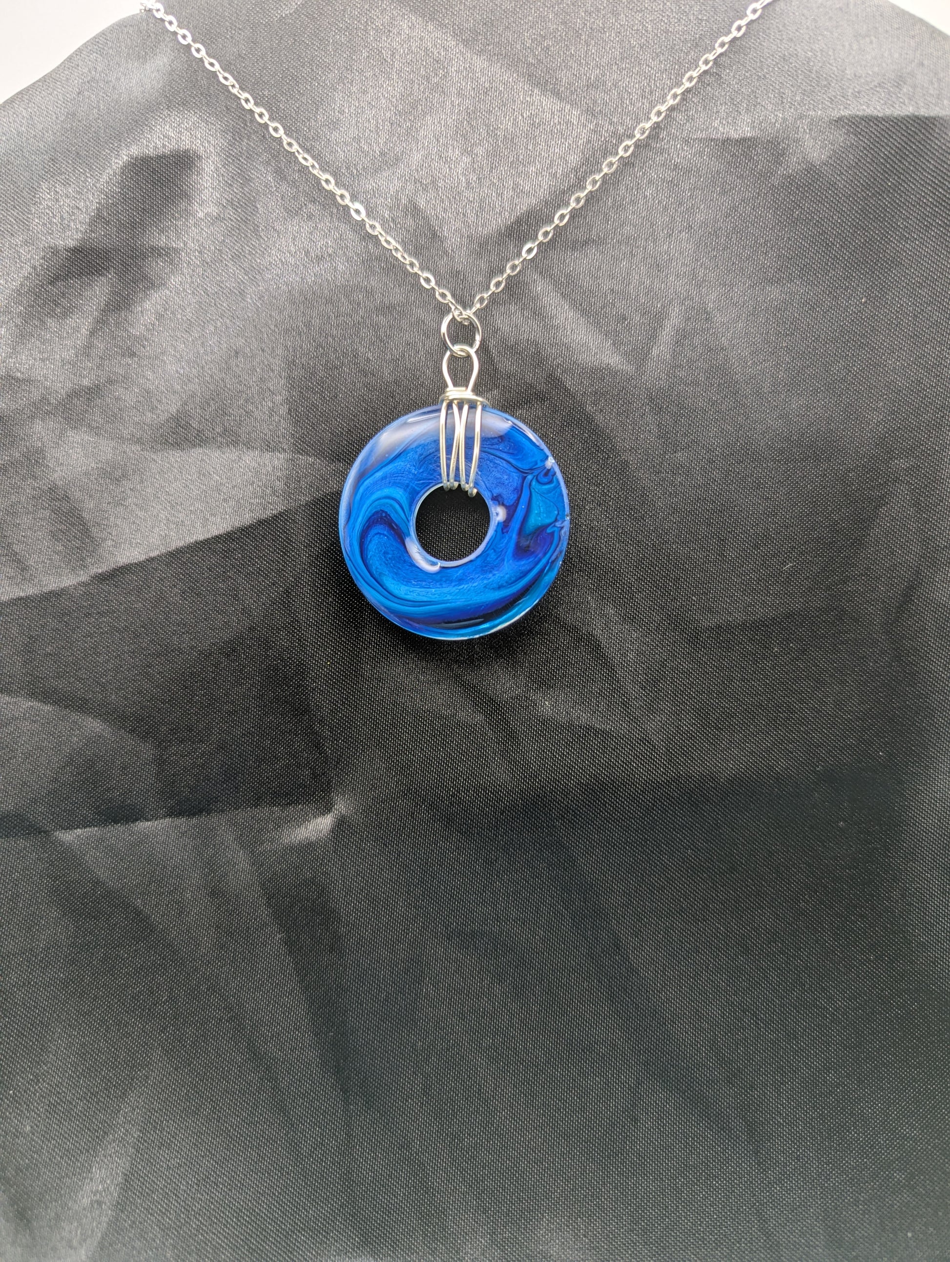 Back view of Wire Wrapped Donut Resin Pendant Necklace - Petri Effect with shades of blue swirls. Resin Necklace on a stainless steel chain