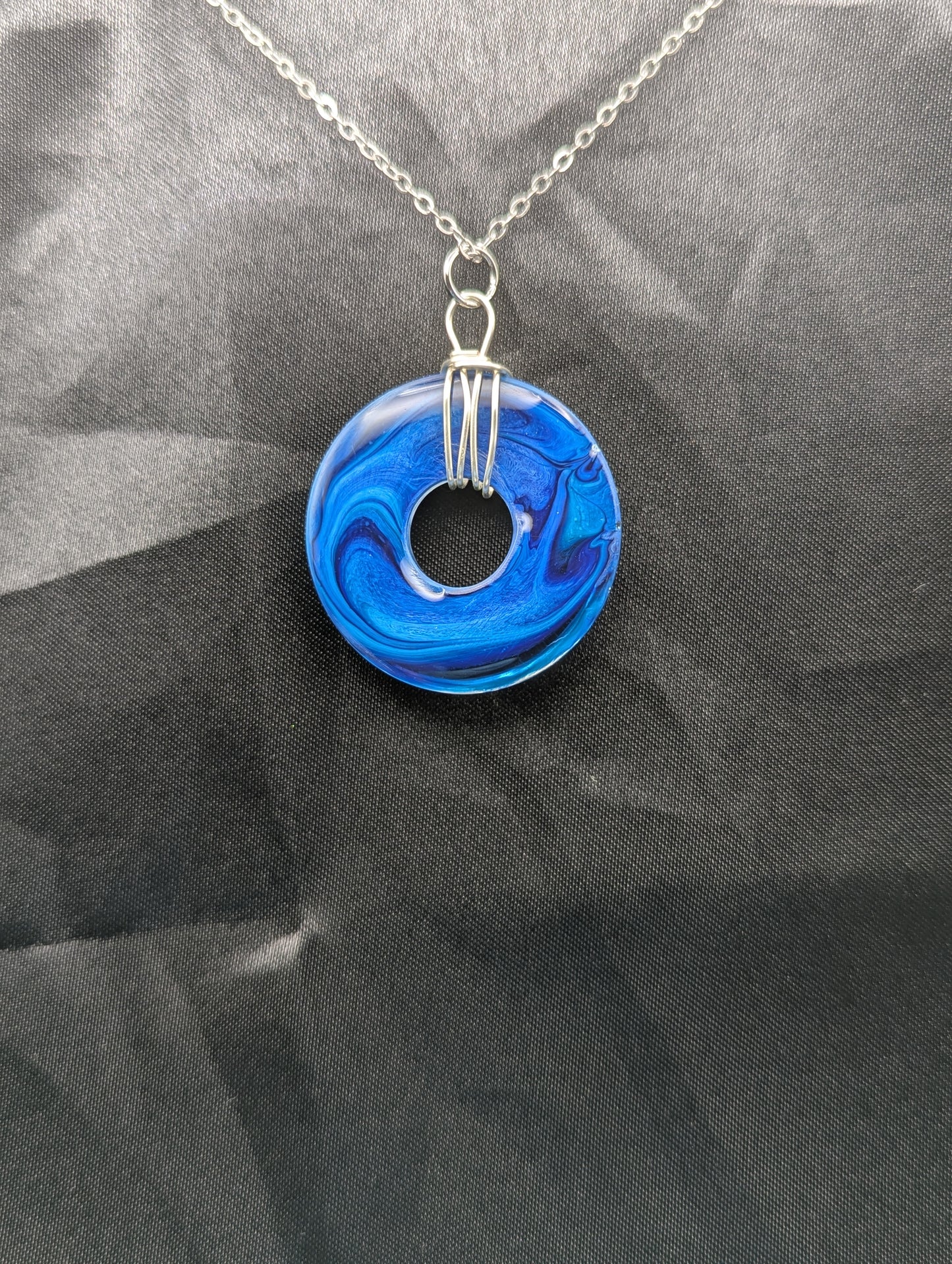Back view of Wire Wrapped Donut Resin Pendant Necklace - Petri Effect with shades of blue swirls. Resin Necklace on a stainless steel chain