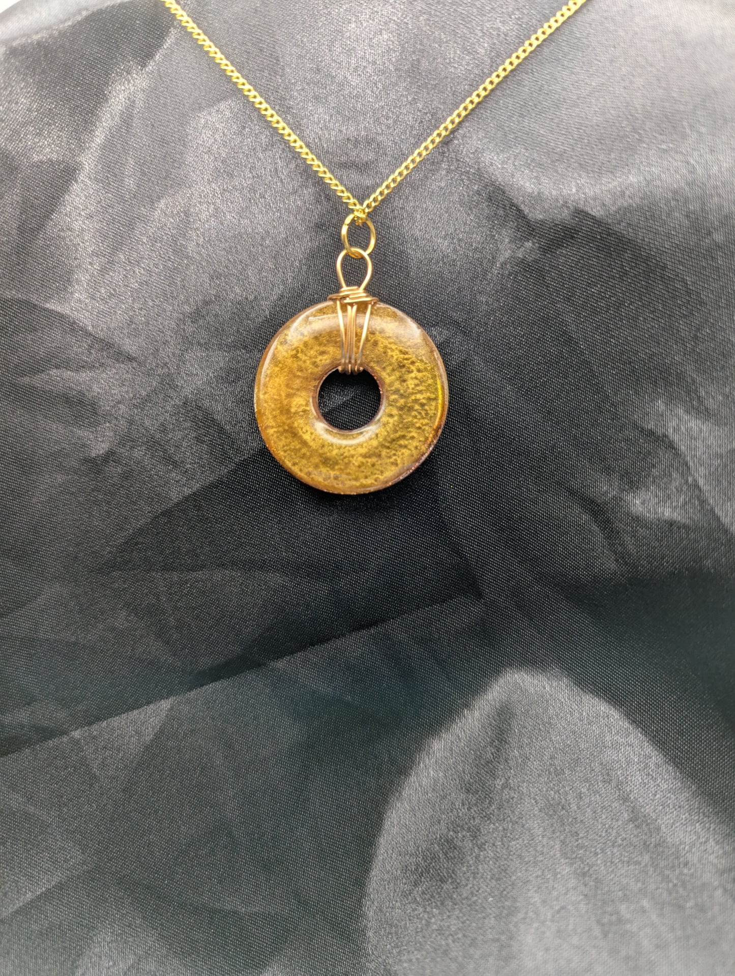 Back view of Wire Wrapped Donut Resin Pendant Necklace - Petri Effect with shades of red & gold swirls. Resin Necklace on a gold plated metal chain.