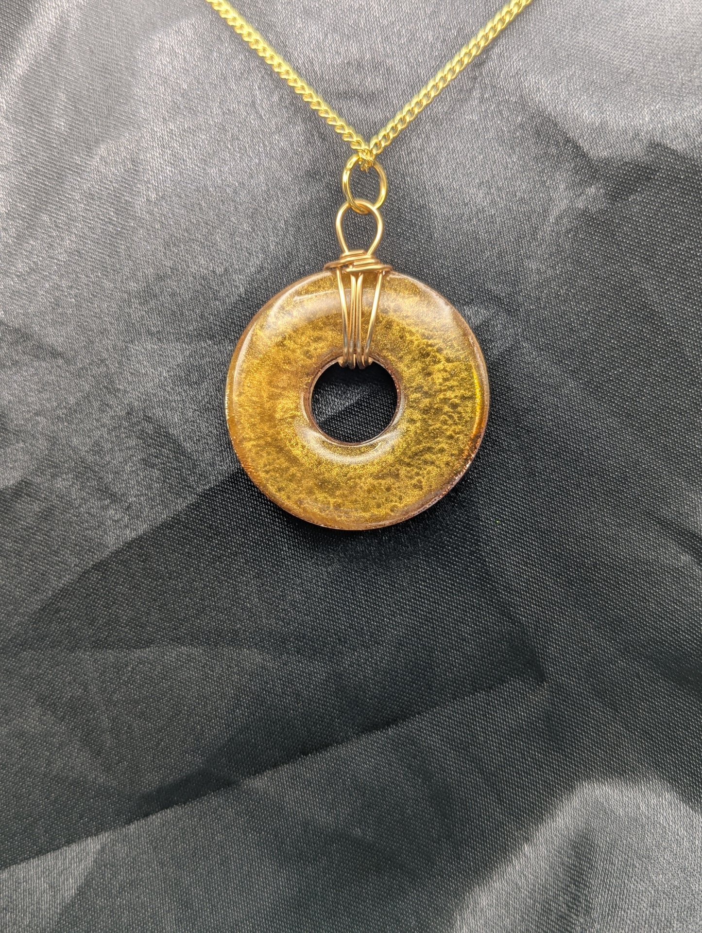 Back view of Wire Wrapped Donut Resin Pendant Necklace - Petri Effect with shades of red & gold swirls. Resin Necklace on a gold plated metal chain.