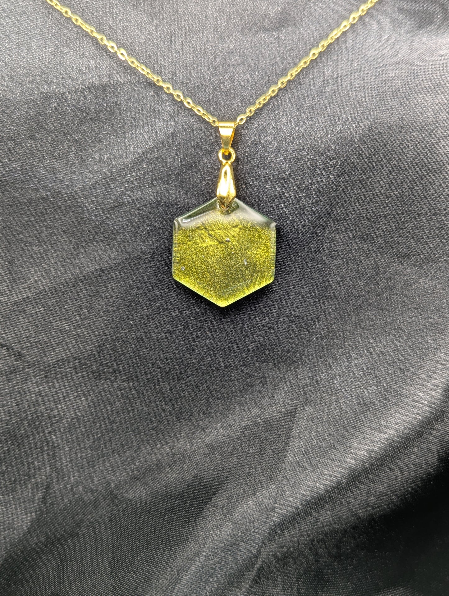 Yellow Hexagon Pendant Necklace with a color shifting background. Resin pendant on a gold pinch bail & gold plated metal chain.