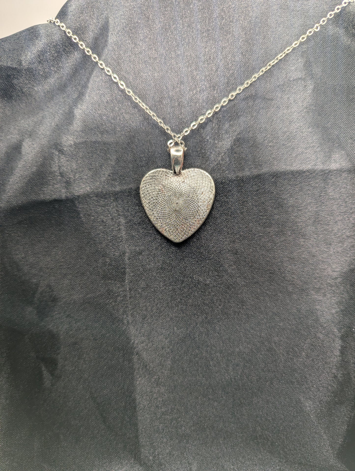 Back view of Silver colored heart shaped metal bezel filled with a transparent sparkly red resin. Resin pendant necklace on a stainless steel chain.