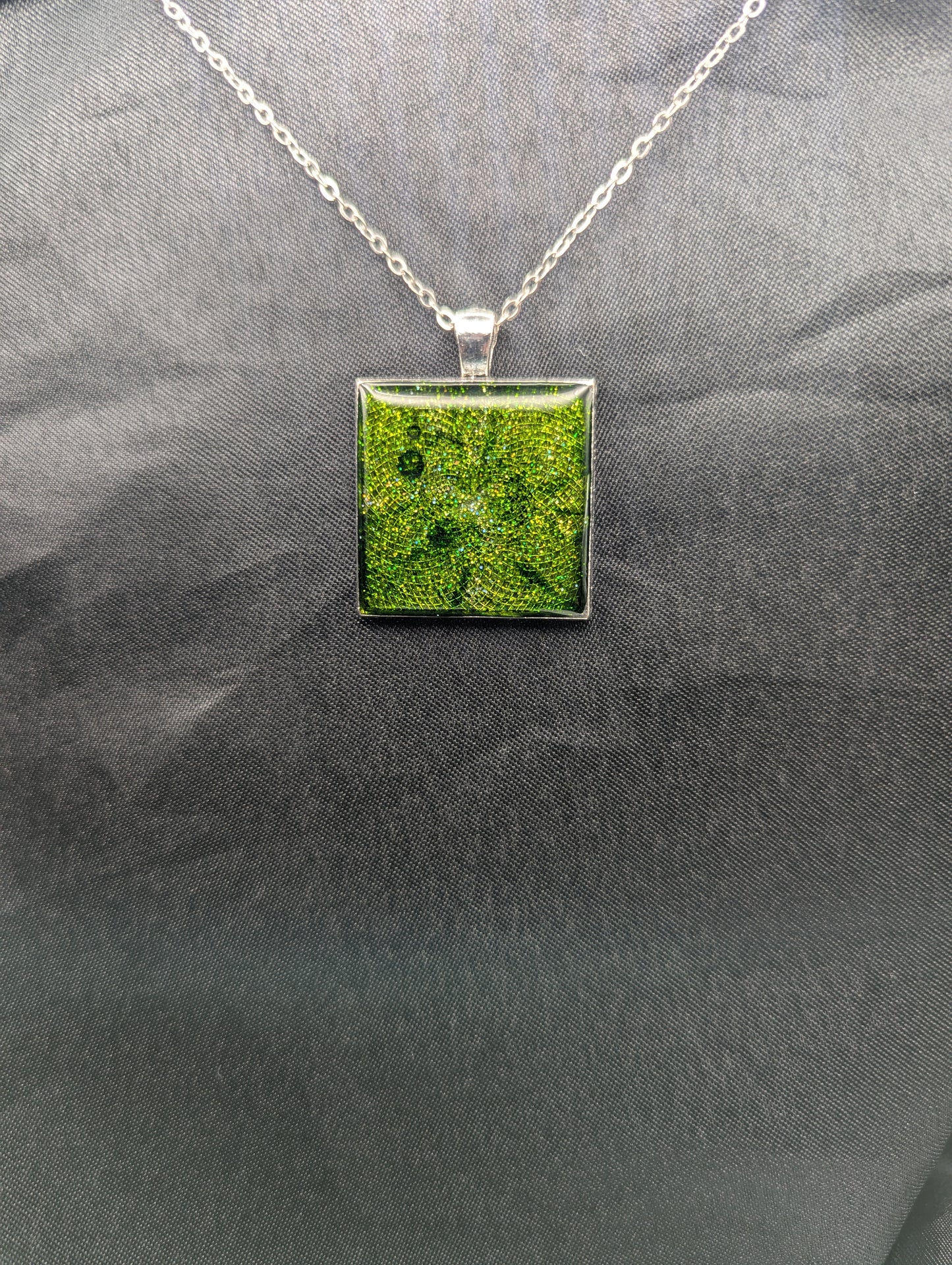 Silver square bezel filled with sparkly green resin. Resin pendant necklace on a stainless steel chain.