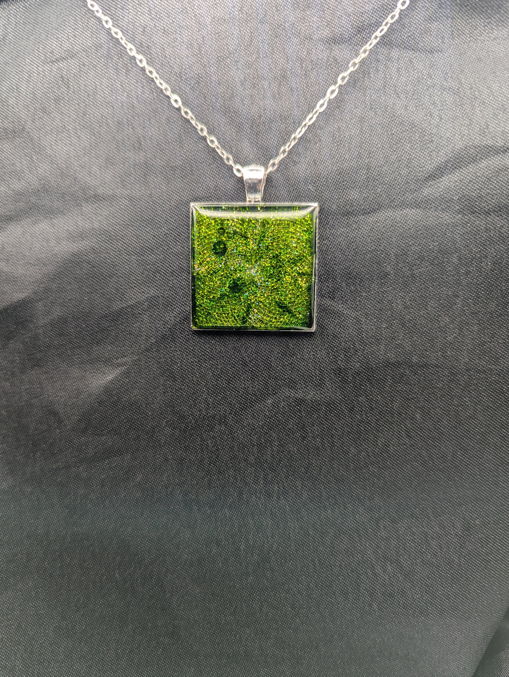 Silver square bezel filled with sparkly green resin. Resin pendant necklace on a stainless steel chain.