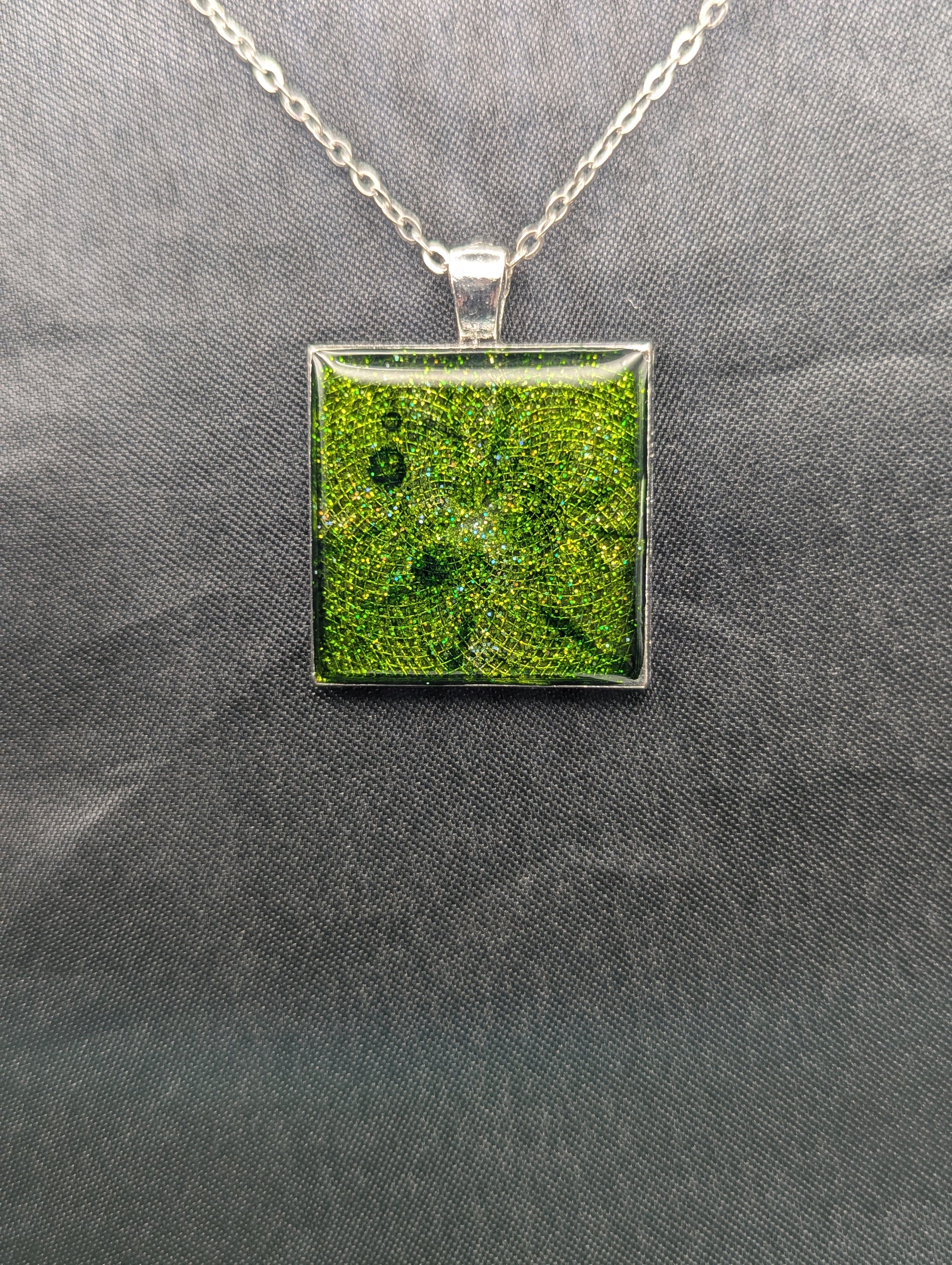 Silver square bezel filled with sparkly green resin. Resin pendant necklace on a stainless steel chain.