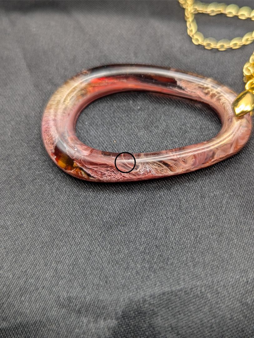 Pink & orange Zero Shaped Resin Pendant Necklace - Petri Effect with shades of pink, orange, & red swirls. Resin Necklace on a gold pinch bail & gold plated metal chain.