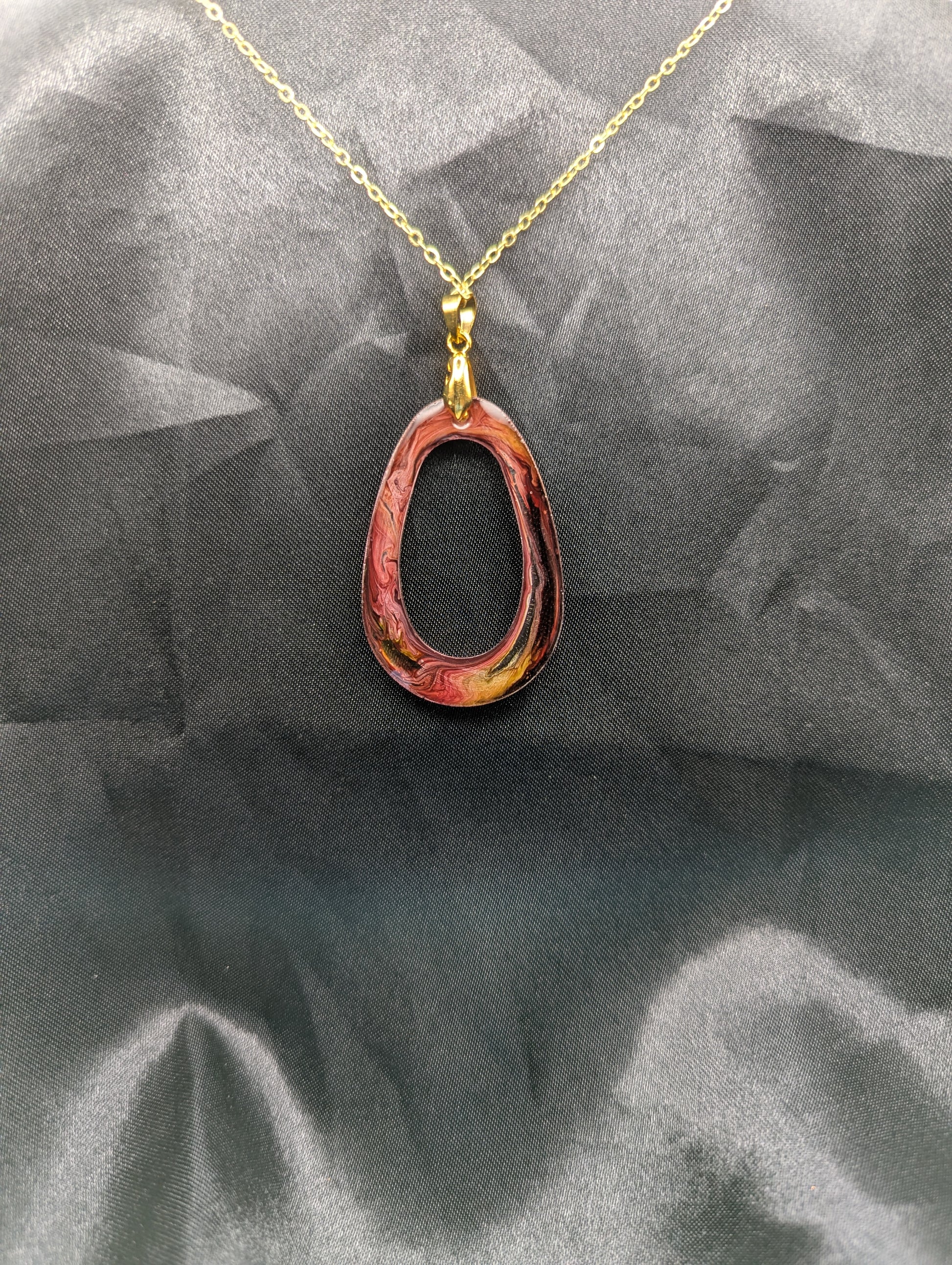 Back view of Pink & Orange Zero Shaped Resin Pendant Necklace - Petri Effect with shades of pink, orange, & red swirls. Resin Necklace on a gold pinch bail & gold plated metal chain.