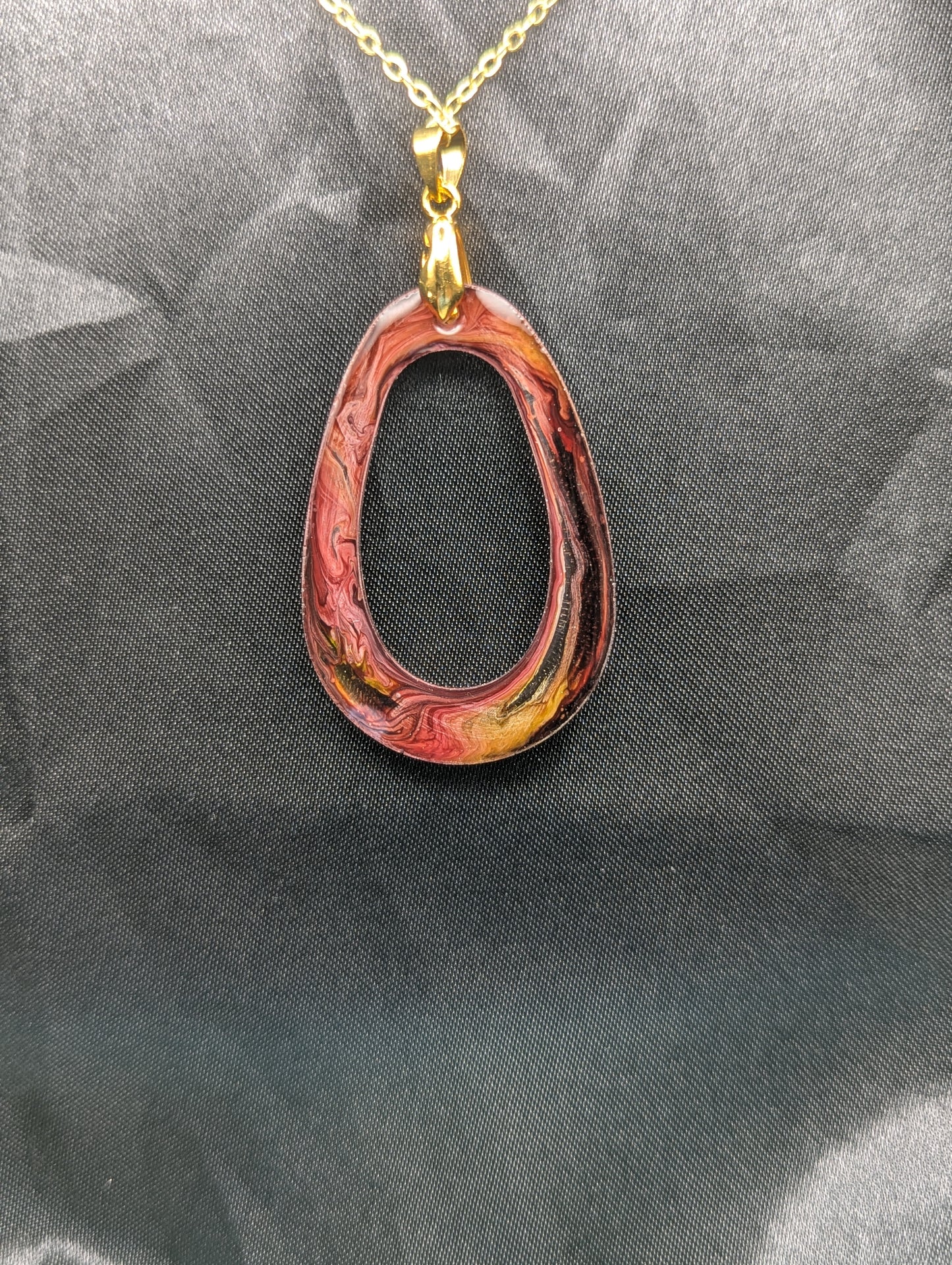 Back view of Pink & Orange Zero Shaped Resin Pendant Necklace - Petri Effect with shades of pink, orange, & red swirls. Resin Necklace on a gold pinch bail & gold plated metal chain.