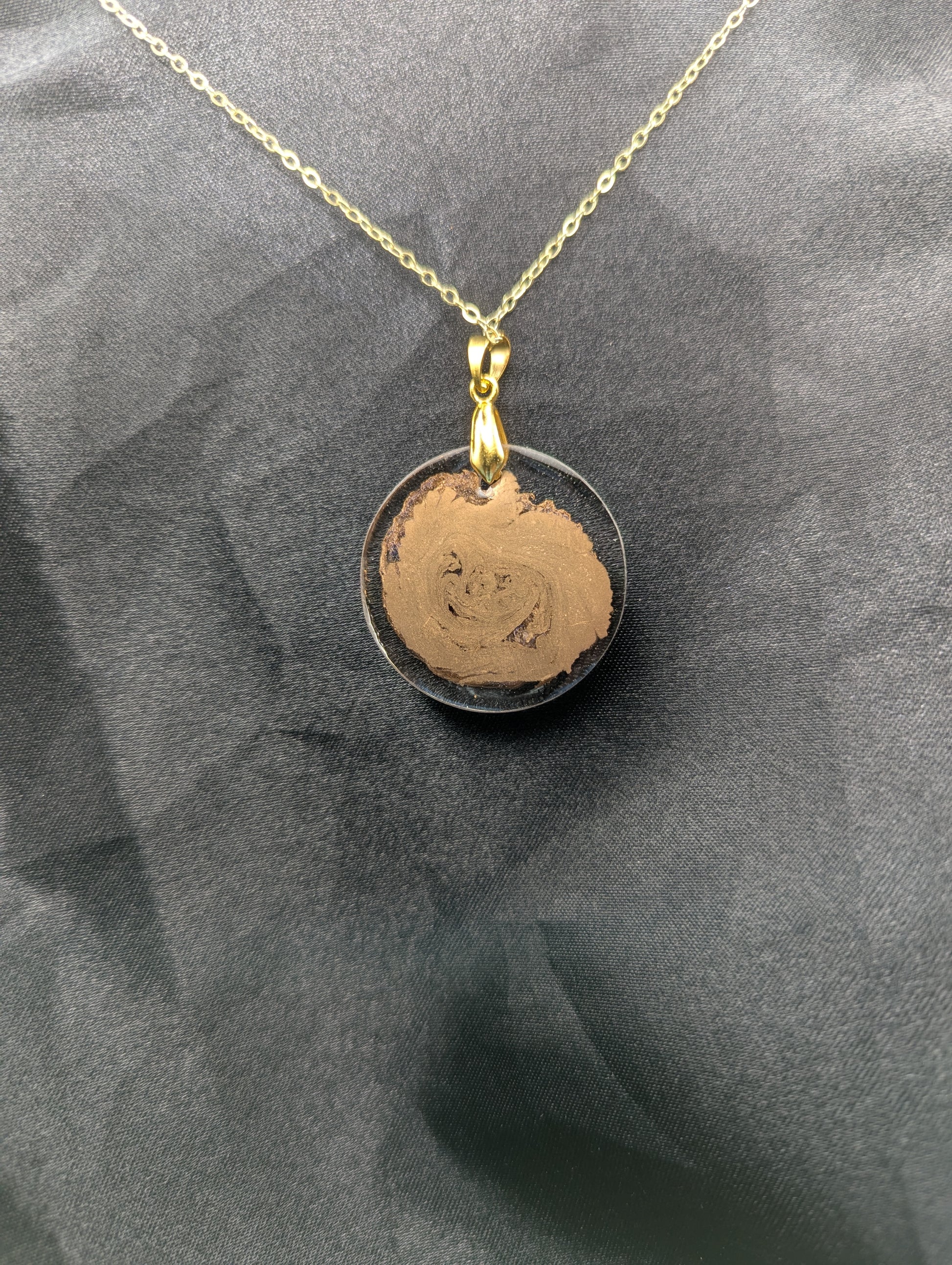 Back view of Gold Swirl Circle Resin Pendant with gold pinch bail on a gold plated metal chain.