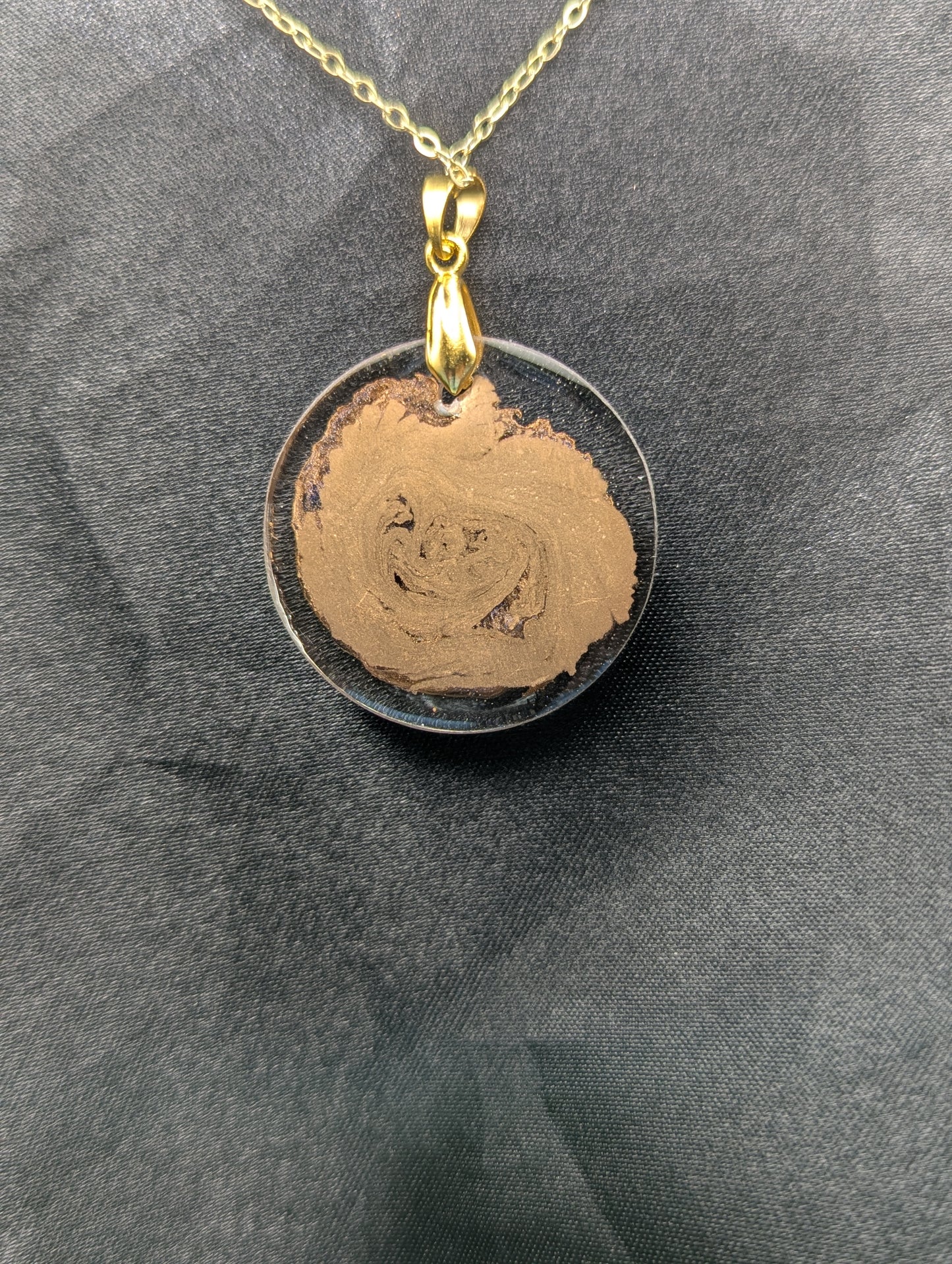 Back view of Gold Swirl Circle Resin Pendant with gold pinch bail on a gold plated metal chain.