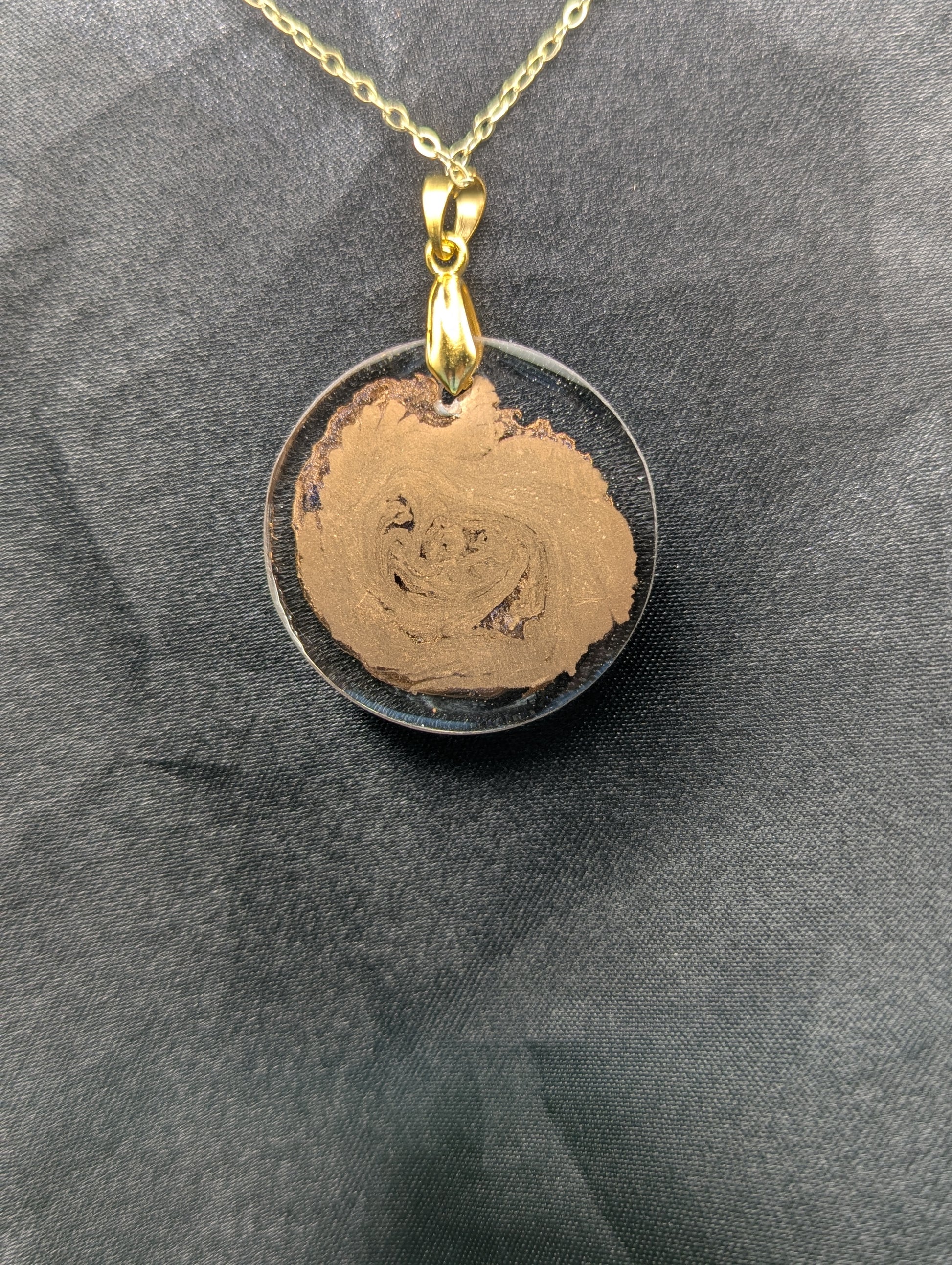 Back view of Gold Swirl Circle Resin Pendant with gold pinch bail on a gold plated metal chain.