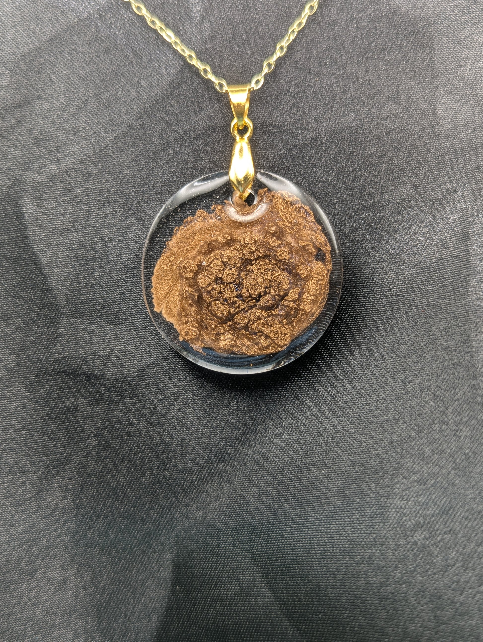 Gold Swirl Circle Resin Pendant with gold pinch bail on a gold plated metal chain.