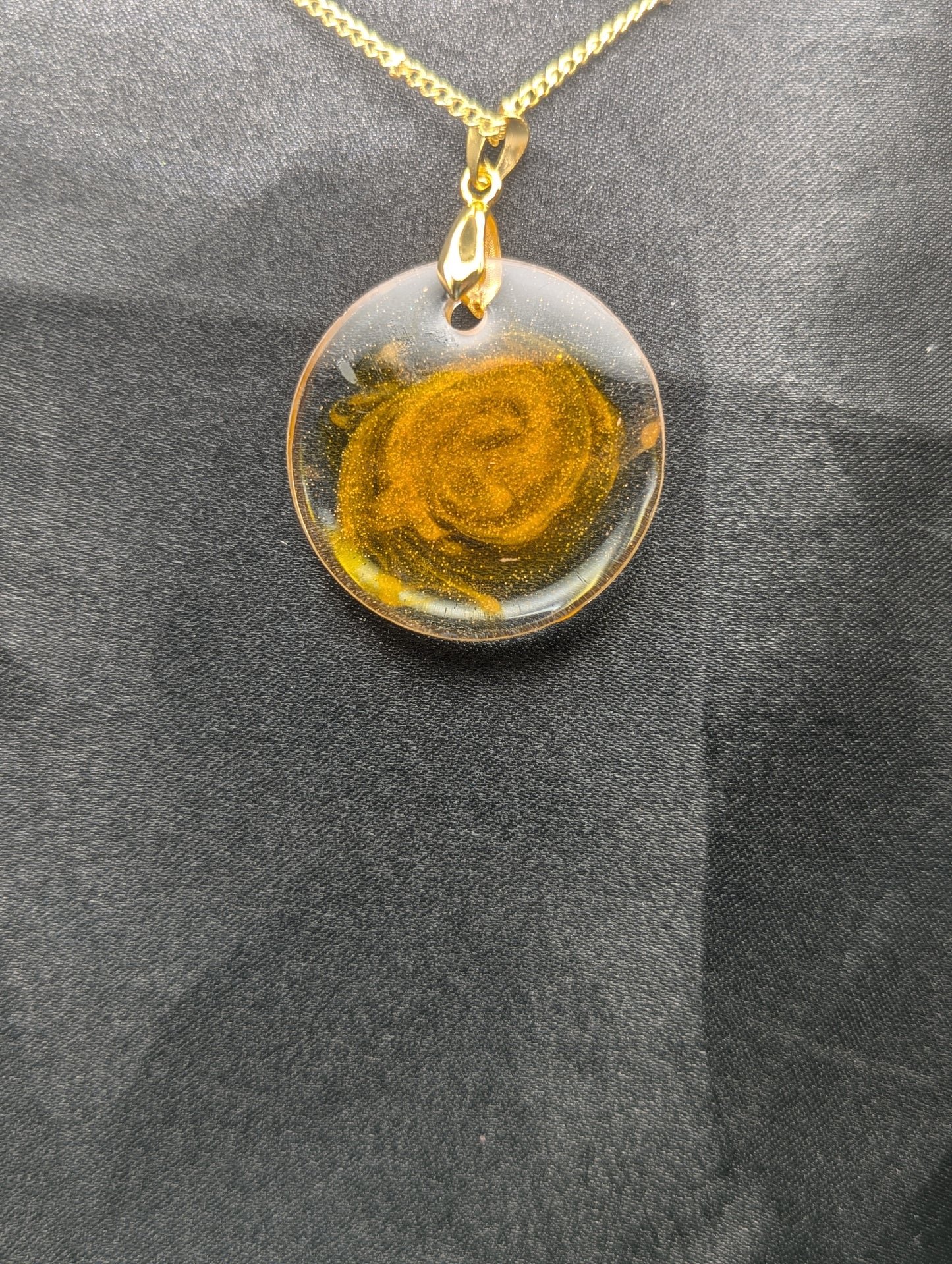 Back view of Yellow & Orange Swirl Circle Resin Pendant with a gold pinch bail on a gold plated metal chain.