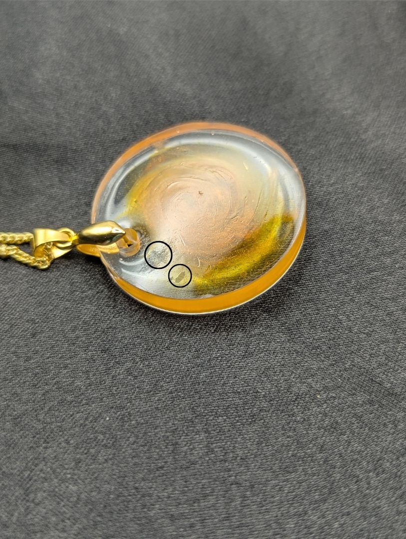 Yellow & Orange Swirl Circle Resin Pendant with a gold pinch bail on a gold plated metal chain.