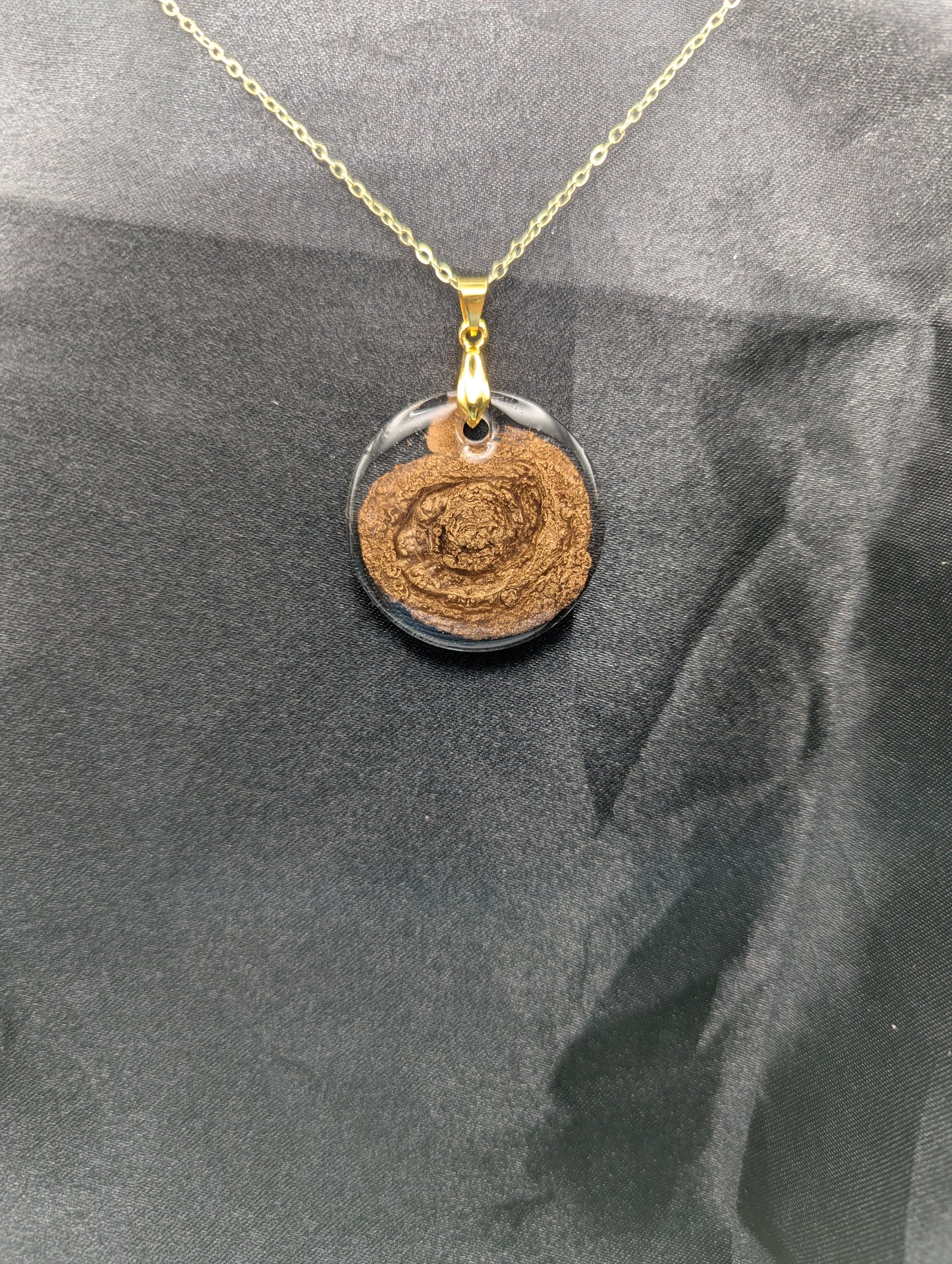 Gold Swirl Resin Circle pendant on a gold pinch bail and gold plated metal chain.