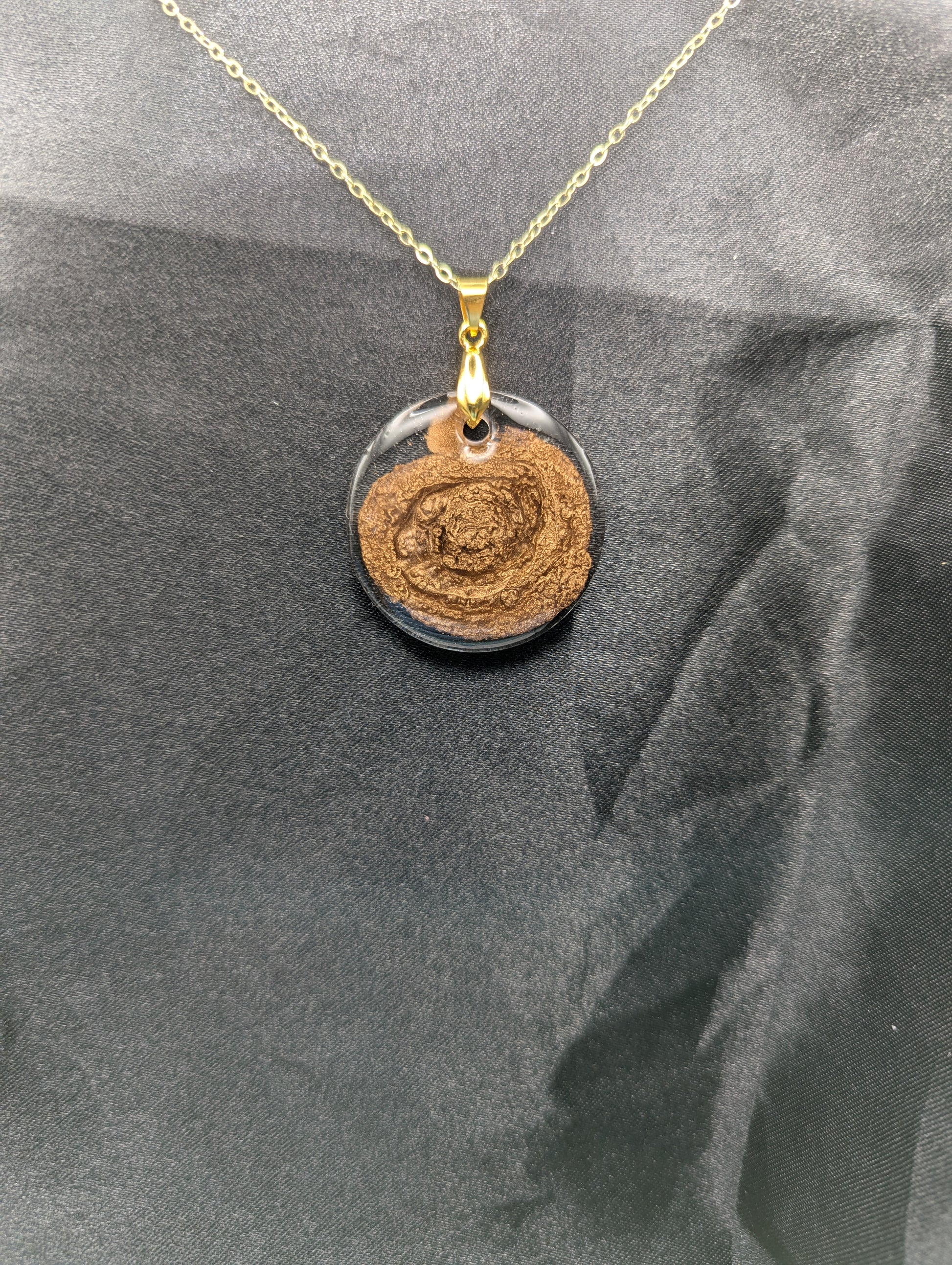 Gold Swirl Resin Circle pendant on a gold pinch bail and gold plated metal chain.